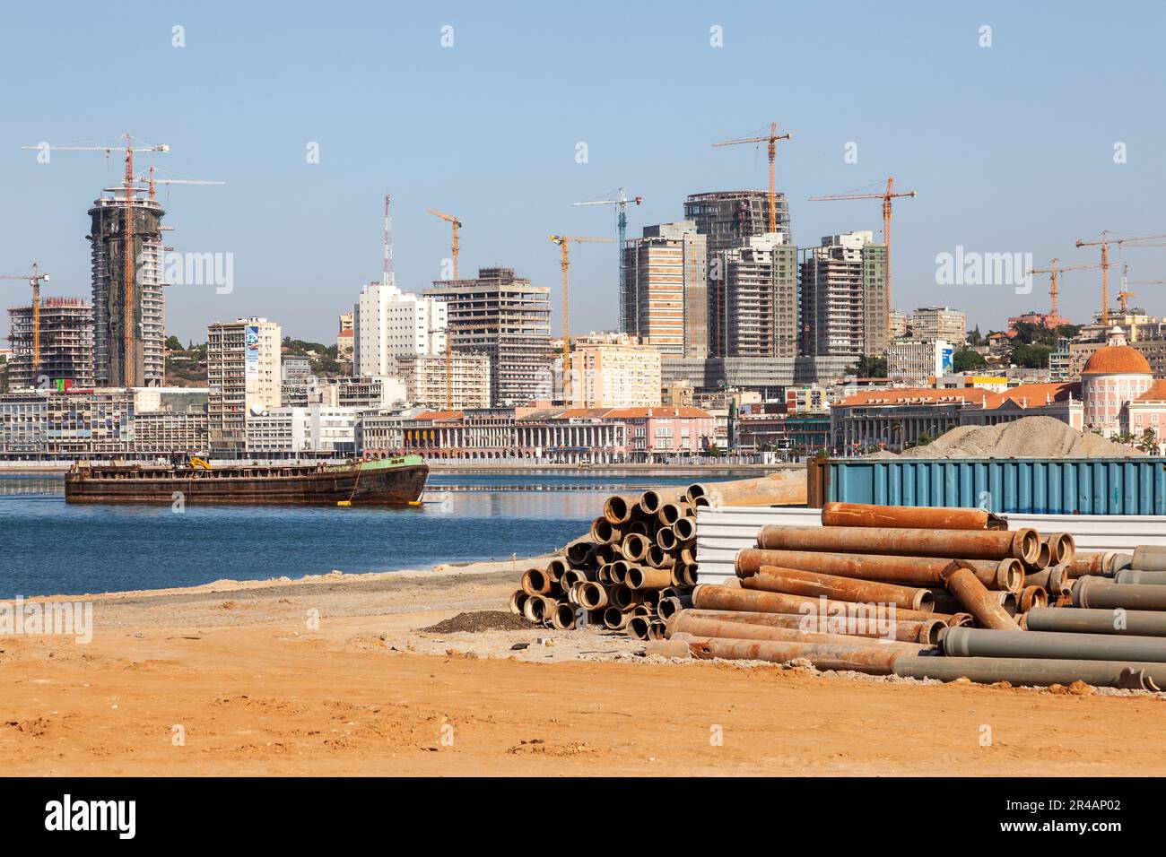 Vista della città costiera di Luanda in fase di ricostruzione, sul bordo della baia. Cantieri edili, pali di tubi.. Foto Stock