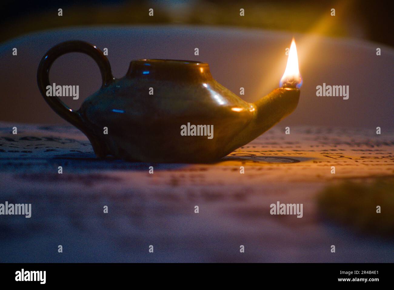 Questa immagine presenta una piccola teiera illuminata da una candela seduta su un tavolo di legno Foto Stock