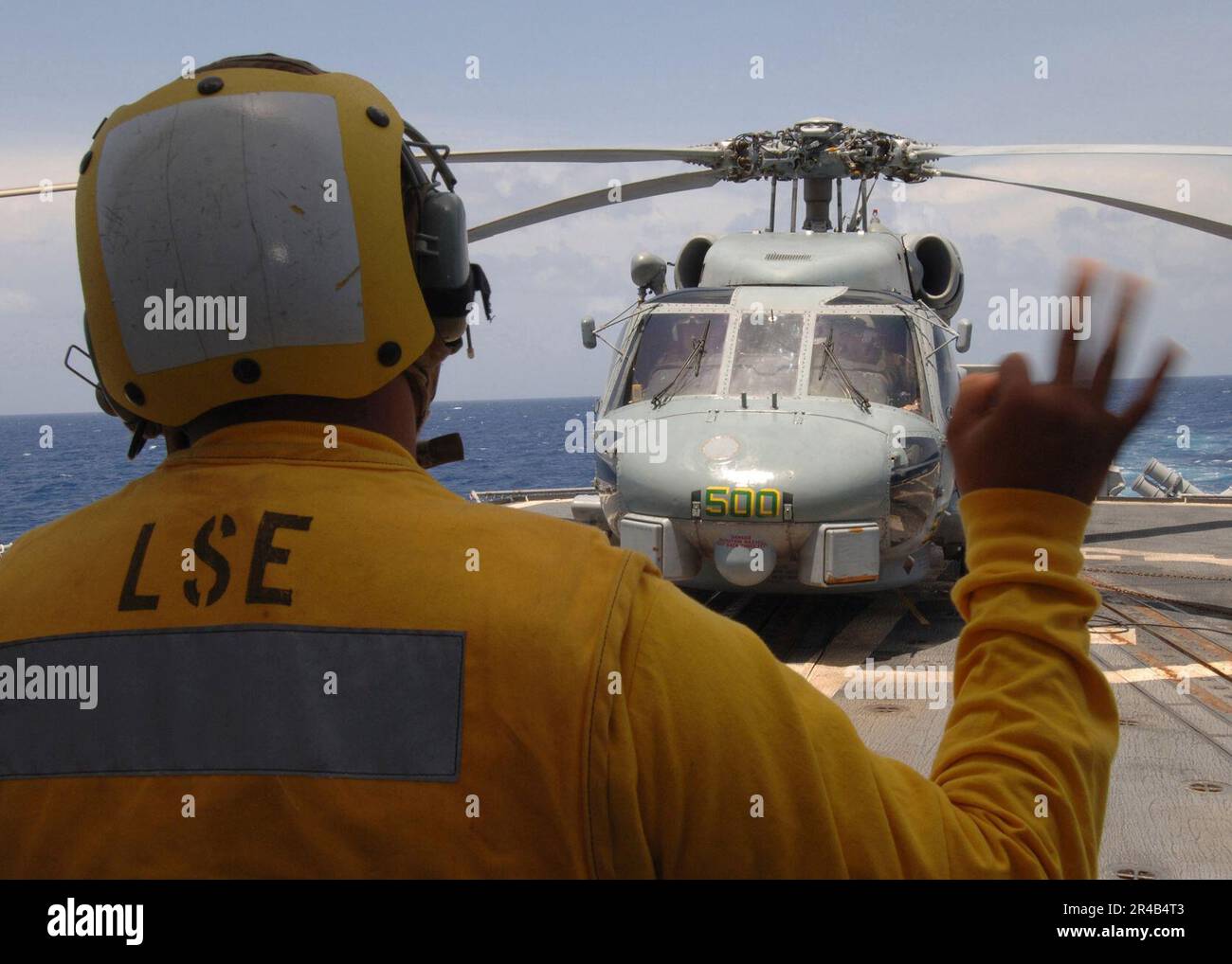 US Navy Un segnale di atterraggio arruolato fornisce un segnale di avviamento iniziale ai piloti a bordo di un elicottero SH-60B Seahawk. Foto Stock