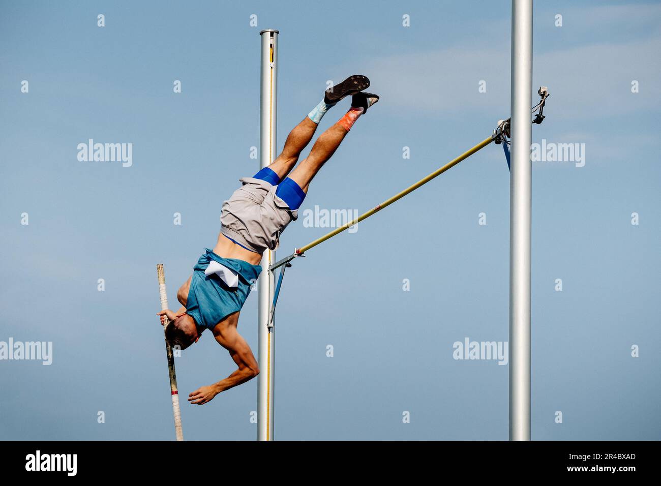atleta maschile salto pole volta nei campionati estivi di atletica su sfondo cielo blu Foto Stock