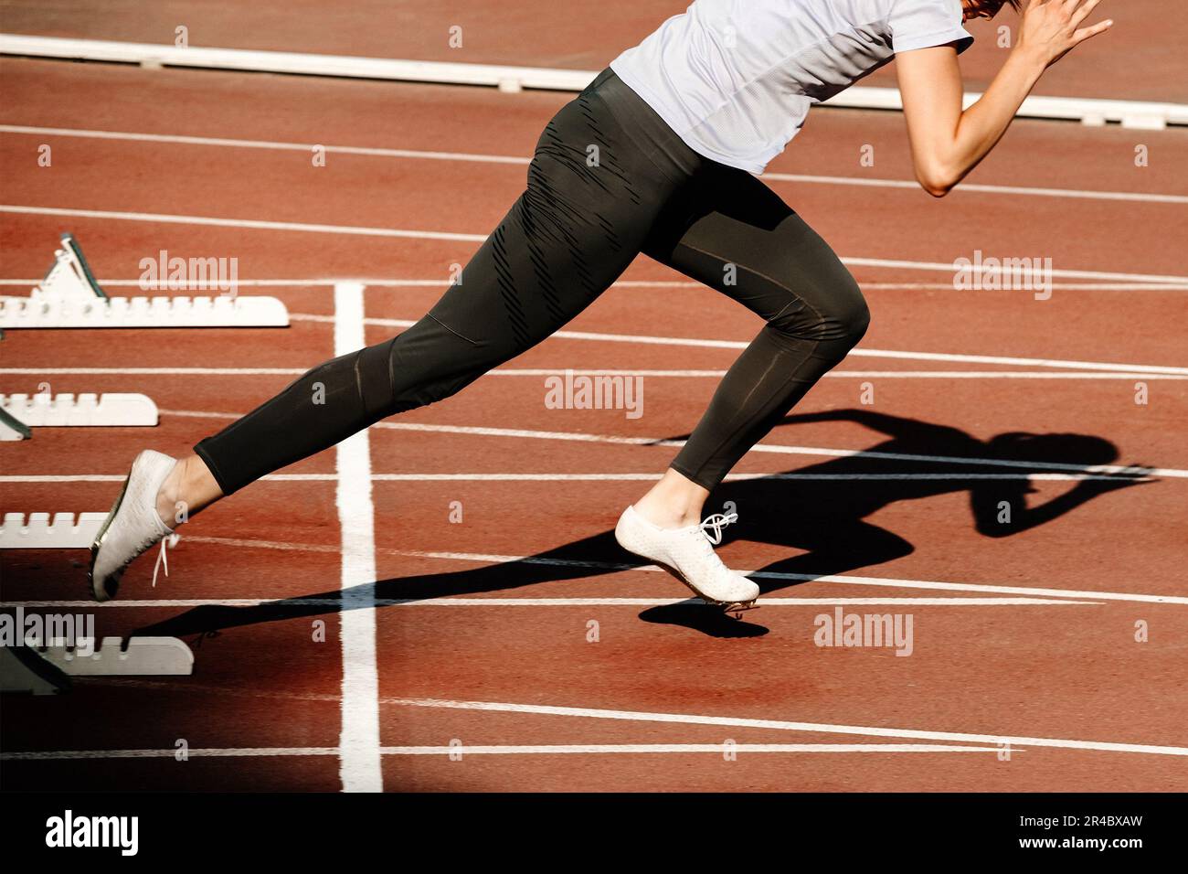 donna sprinter iniziare a correre da blocchi di partenza 100 metri di gara nei campionati di atletica estiva Foto Stock