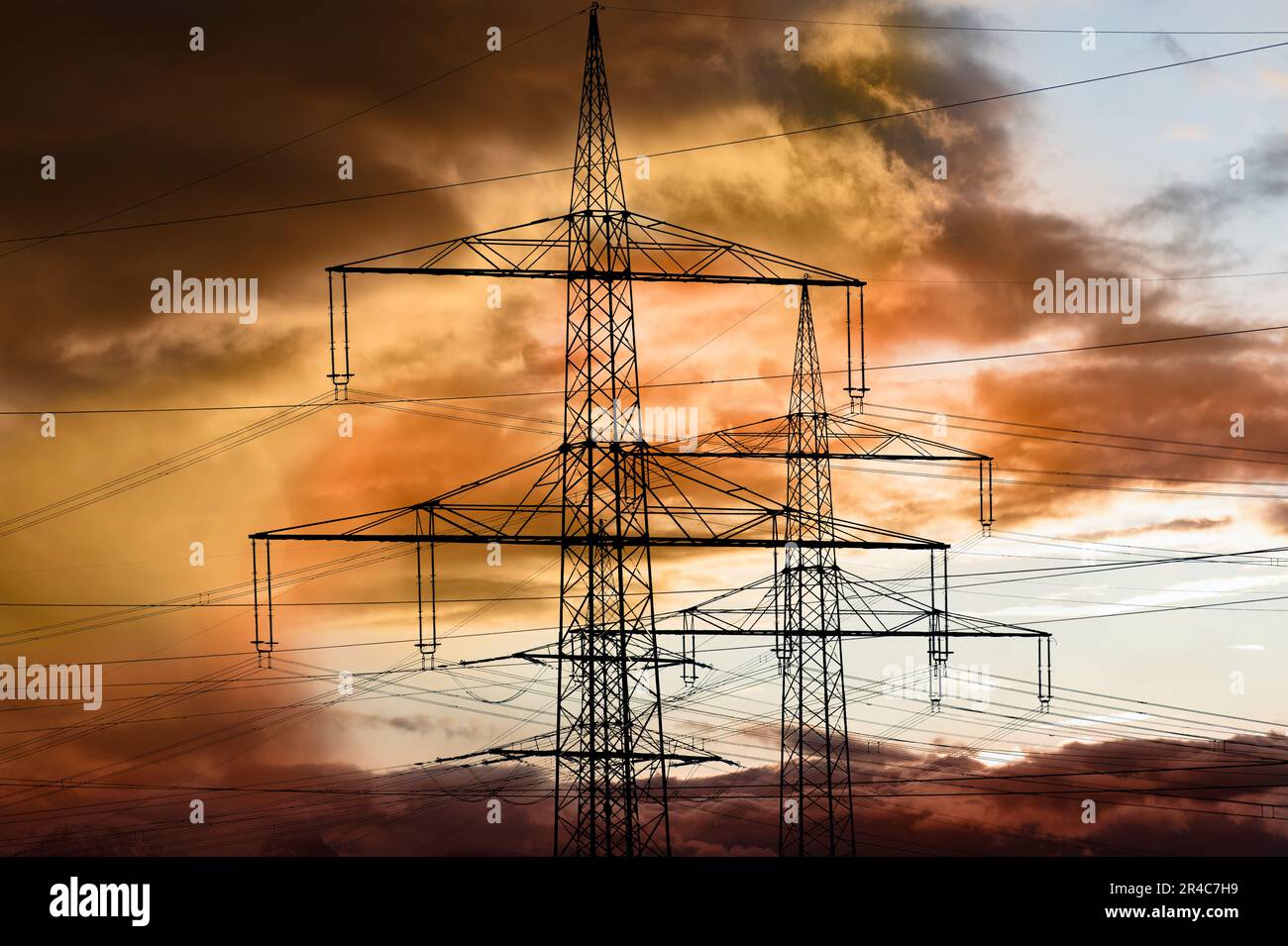 piloni elettrici ad alta tensione contro il cielo con nuvole drammatiche Foto Stock
