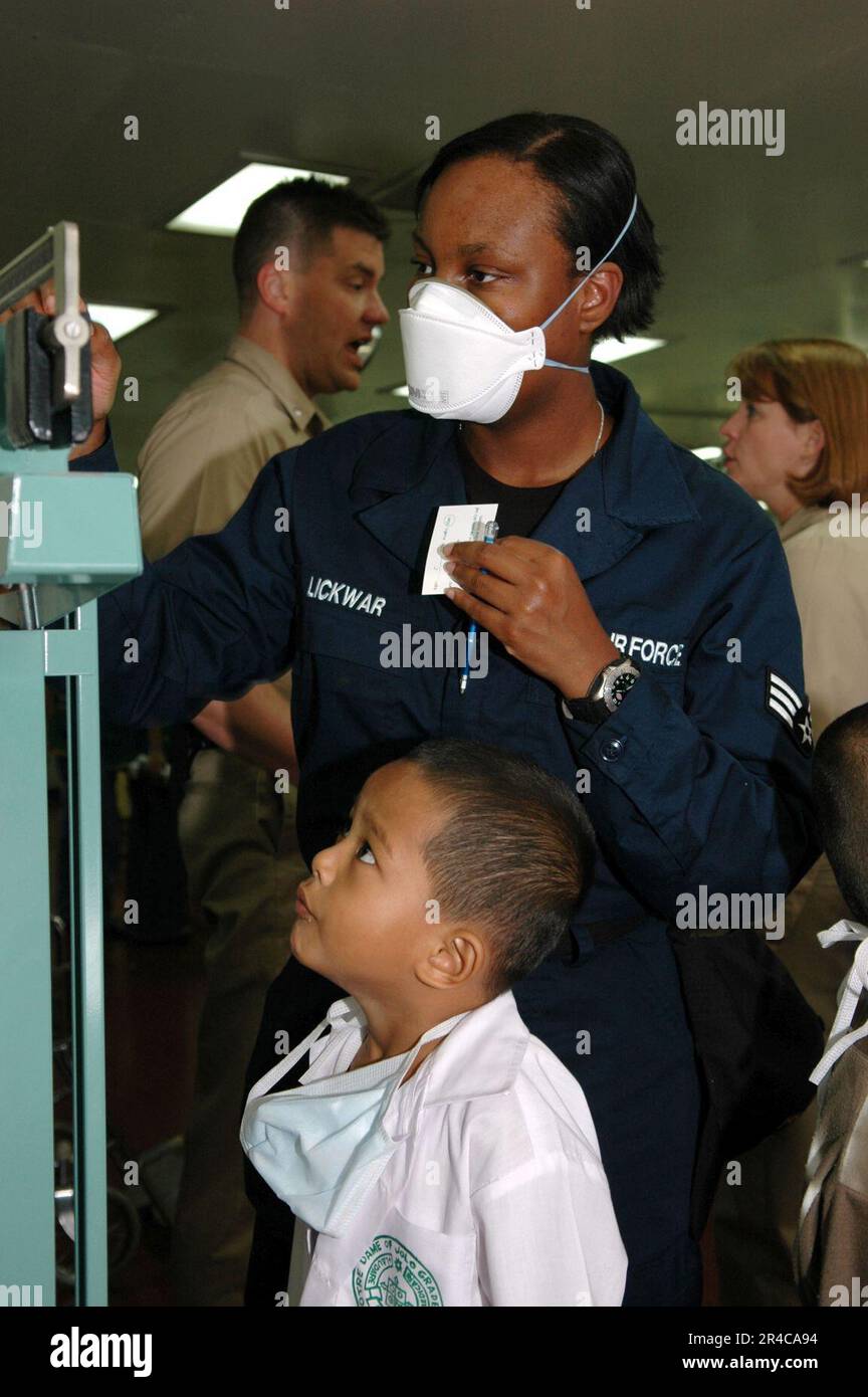 US Navy Air Force Senior Airman pesa un bambino durante un Medical and Dental Civil Action Project a bordo degli Stati Uniti Comando militare di Sealift (MSC) nave ospedaliera USNS. Foto Stock