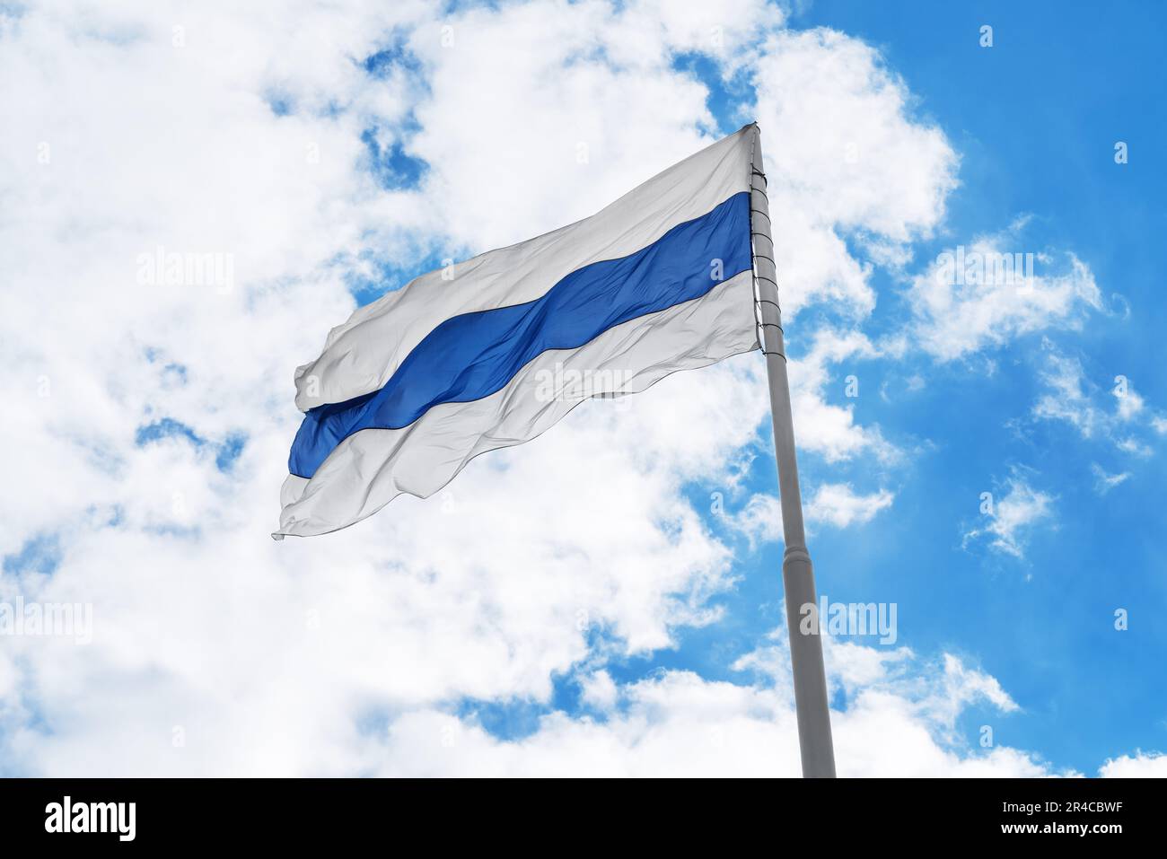 La bandiera russa di protesta bianco-blu-bianco sta sventolando di fronte al cielo blu e alle nuvole. Foto Stock