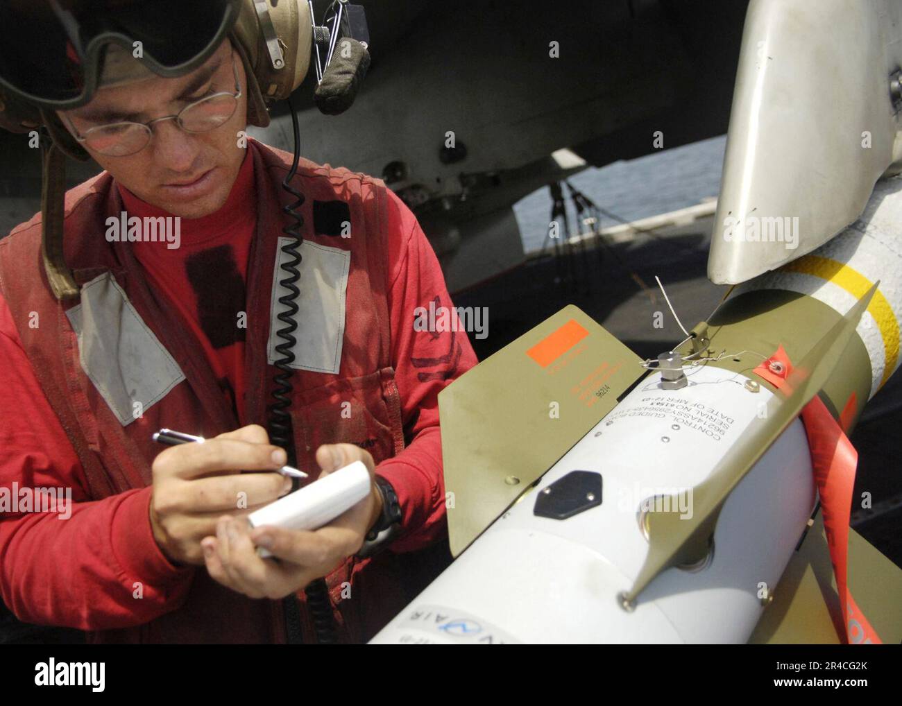 US Navy Aviation Ordnanceman 2nd Class verifica i numeri di serie sui componenti di una bomba guidata al laser GBU-12. Foto Stock