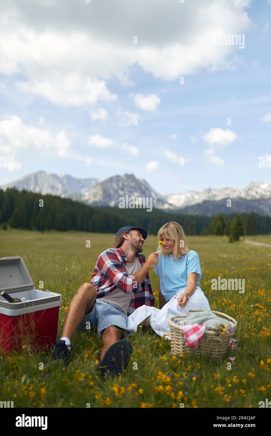 Una coppia felice sta facendo un picnic su un prato in una bella giornata di sole sulle montagne. Relazione, natura, attività, amore Foto Stock