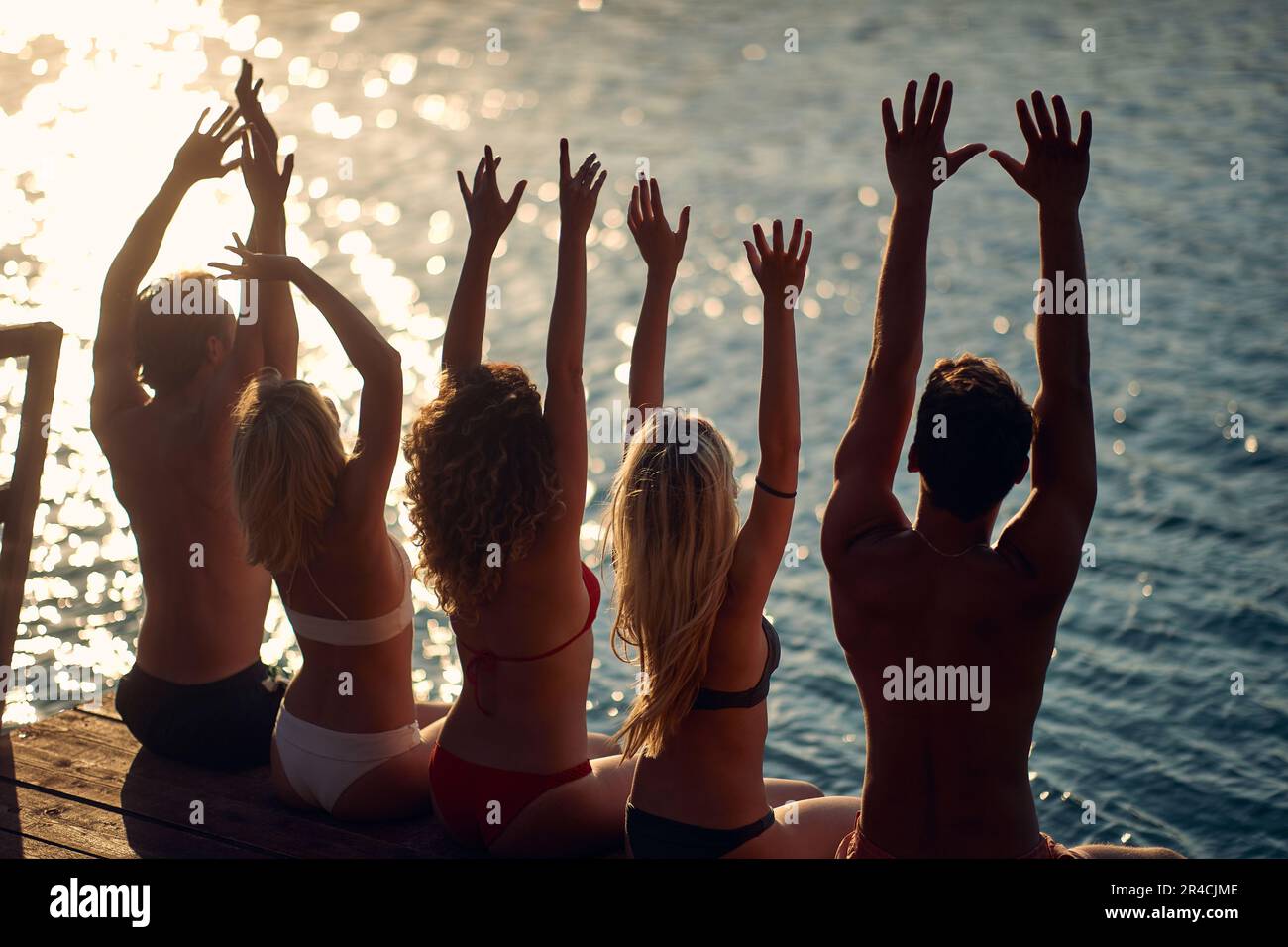 Gruppo di amici che prendono il sole la giornata estiva insieme sul lago Foto Stock