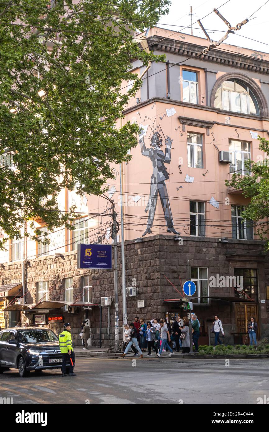 Il musicista graffiti murali, compositore direttore murale. Poliziotto stradale a Erevan con persone che attraversano la strada Foto Stock