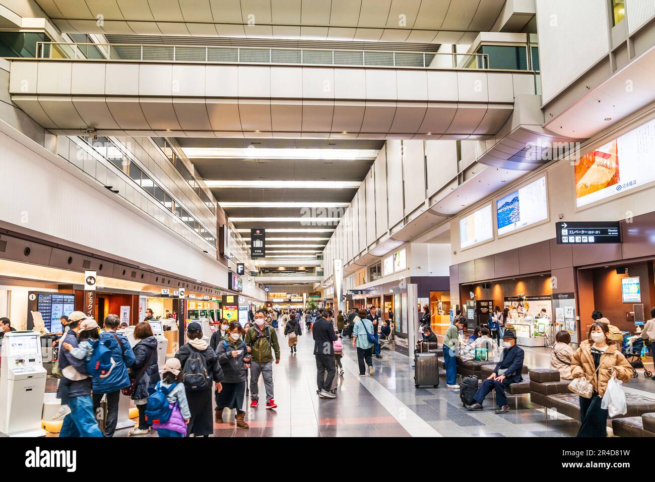 Vista lungo l'interno del terminal nazionale 1 presso l'aeroporto Haneda Tokyo, banco check-in da un lato e negozi al dettaglio dall'altro. Foto Stock