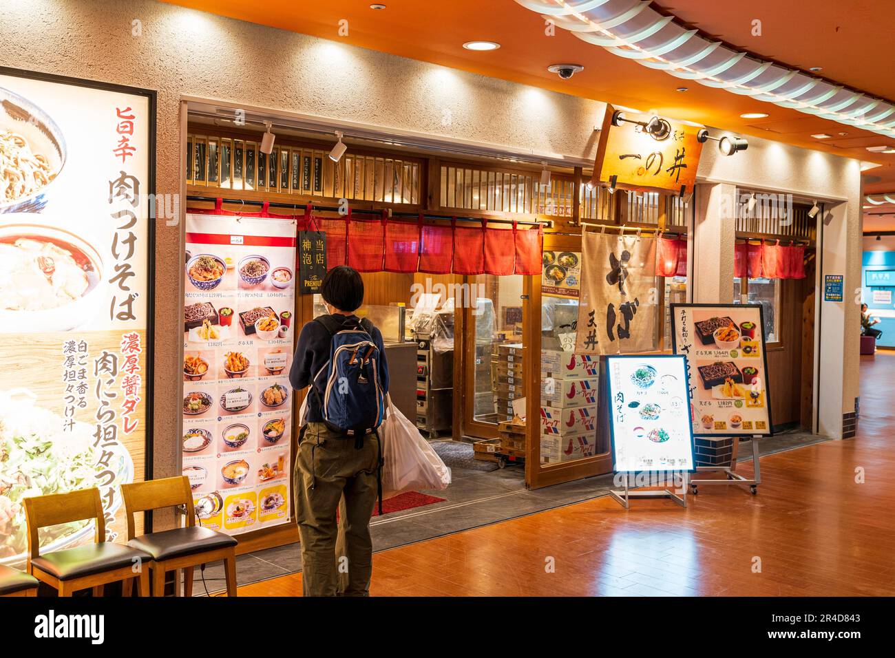 Ristorante Ichinoi Ramen noodle al terzo piano del terminal 1, aeroporto di Haneda. Uomo in piedi all'esterno che guarda il menu delle pareti, tende noren sopra l'entrata. Foto Stock
