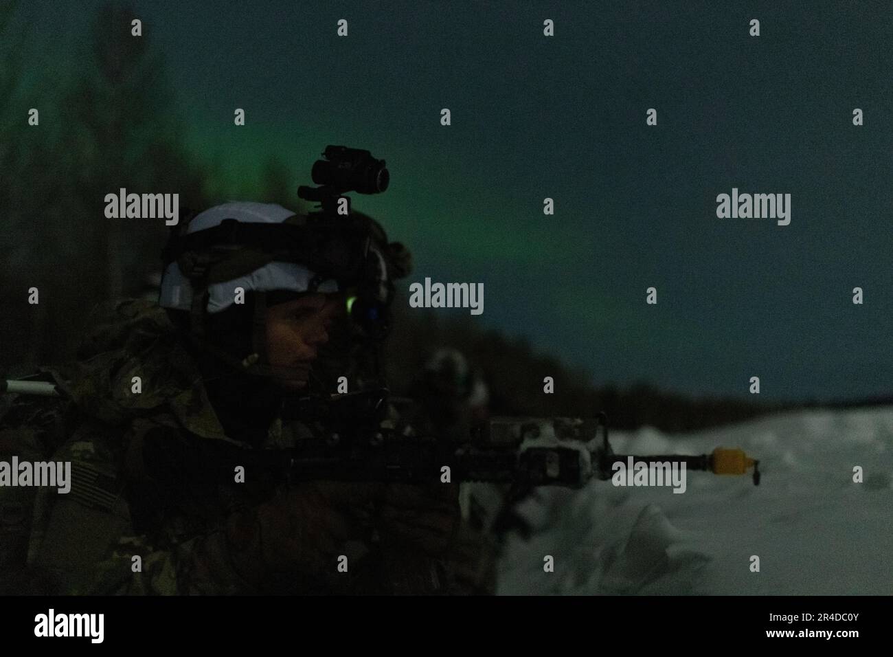 L'aurora borealis illumina il cielo notturno come gli Stati Uniti I paracadutisti dell'esercito assegnati alla squadra di combattimento della Brigata di Fanteria 2nd (Airborne), 11th Airborne Division, assaltano una zona di atterraggio durante il Joint Pacific Multinational Readiness Center-Alaska 23-02 presso Yukon Training Area, ft. Wainwright, Alaska, 30 marzo 2023. L’Artico è spietato e richiede leader intenzionali e mirati, meticolosi nella pianificazione e nell’approccio ai combattimenti di guerra, e JPMRC-AK 23-02 è fondamentale per testare i leader e i soldati della divisione. Foto Stock