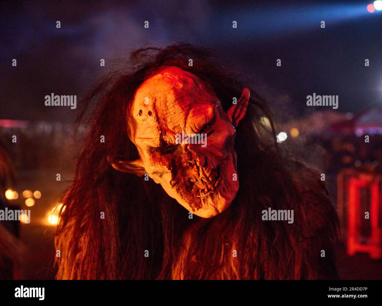 Un gruppo di persone vestite con maschere facciali inquietanti illuminate da un lampione di notte Foto Stock