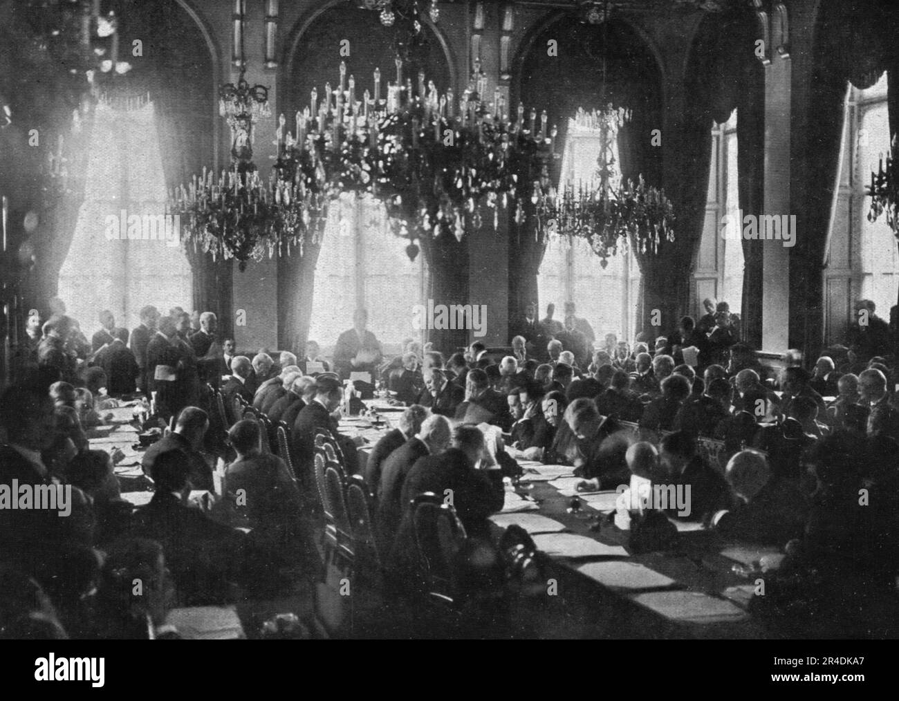 « La naissance de la societe des Nations; le 28 avril 1919, au cours de la cinquieme s&#xe9;ance pleniere de la Conference de la Paix, dans la grande salle a manger du ministere des Affaires etrangeres, le president Wilson, debout devant la fenetre du milieu, donne lecture du pacte qui constitue la Societe des Nations; au Premier plan a droite, les places vides de MM Orlando et Sonnino qui ont momentanement quitte la Conference et sont rentres a Rome, soulevant un vif incidente a la suite du refus du president Wilson d'admettre les revendications de l'Italie sur le port de Fiume', 1919. Da &qu Foto Stock