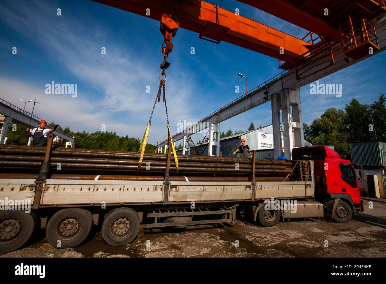 Podolsk, provincia di Mosca - 02 agosto 2021: Deposito tubi. I lavoratori caricano i tubi sul carrello con un carroponte Foto Stock