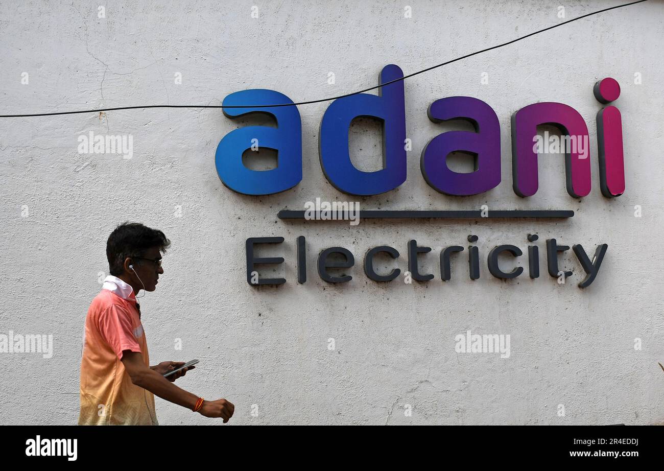 Mumbai, Maharashtra, India. 27th maggio, 2023. Un uomo in possesso di un telefono cellulare passa davanti al logo dell'elettricità Adani sul muro di Mumbai. Adani Power and Energy è una delle più grandi società di distribuzione di energia in India, che fa parte del gruppo di società Adani. (Credit Image: © Ashish Vaishnav/SOPA Images via ZUMA Press Wire) SOLO PER USO EDITORIALE! Non per USO commerciale! Foto Stock