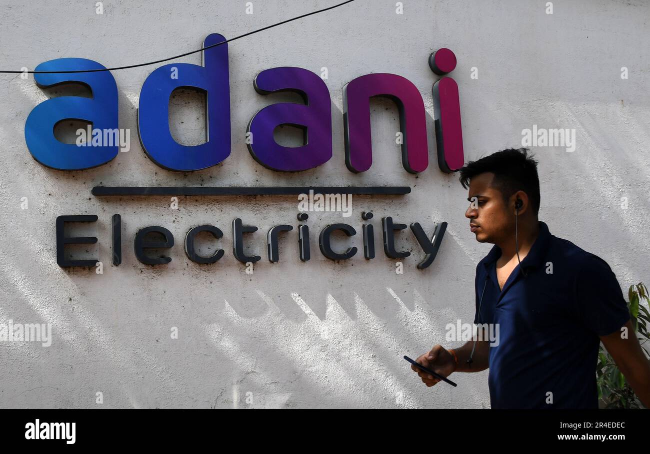 Mumbai, Maharashtra, India. 27th maggio, 2023. Un uomo in possesso di un telefono cellulare passa davanti al logo dell'elettricità Adani sul muro di Mumbai. Adani Power and Energy è una delle più grandi società di distribuzione di energia in India, che fa parte del gruppo di società Adani. (Credit Image: © Ashish Vaishnav/SOPA Images via ZUMA Press Wire) SOLO PER USO EDITORIALE! Non per USO commerciale! Foto Stock