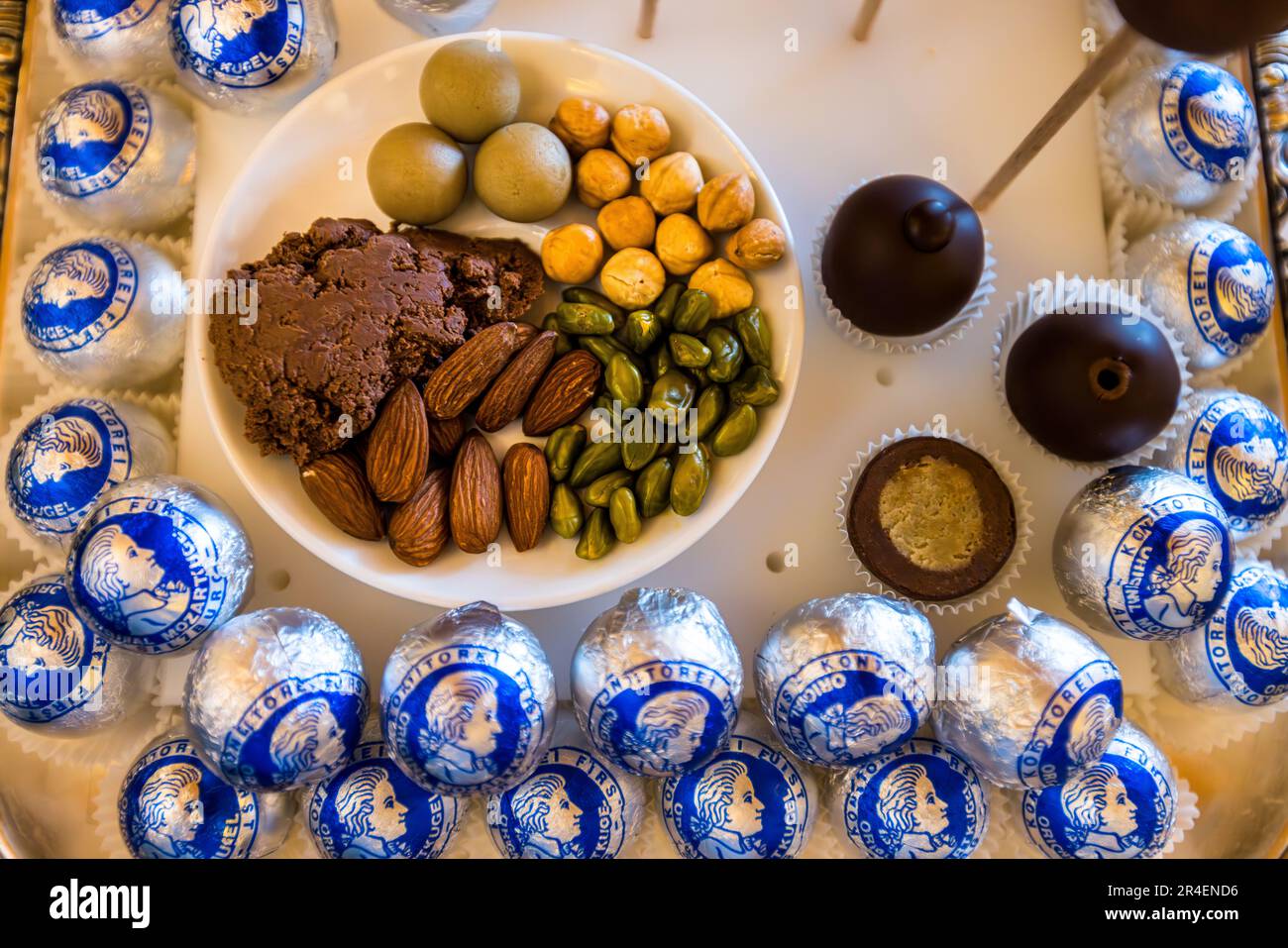 Palline di marzapane verde, nocciole e pezzi di ganache scura giacciono accanto a Mozartkugeln Original di Salisburgo avvolte nella stagnola alla pasticceria Fürst di Salisburgo, Austria – gli ingredienti della pralina inventata dal pasticcere Paul Fürst nel 1890. Foto Stock