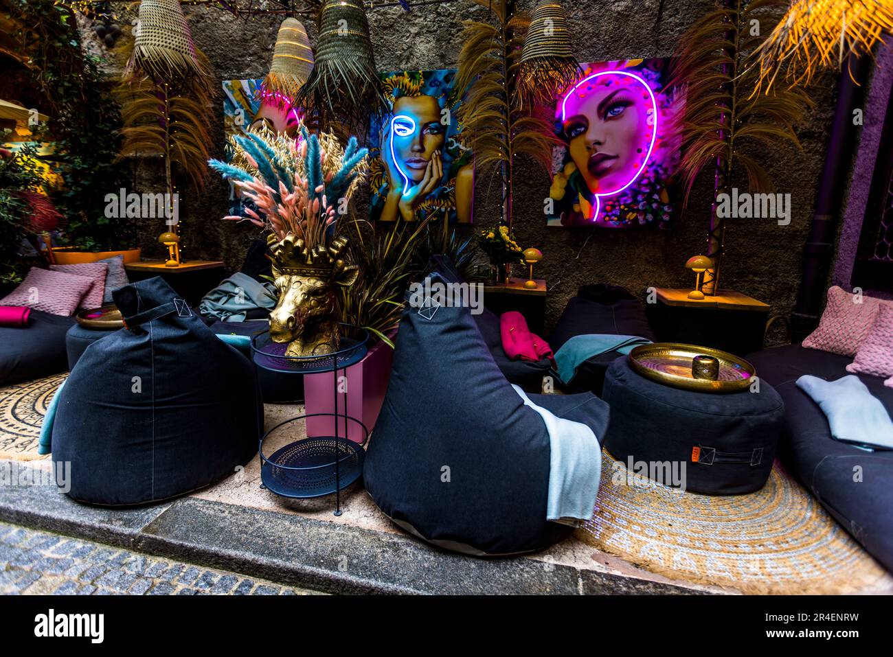 L'atmosfera storica incontra l'arte pop nel lounge esterno del Restaurant Peter allo St Peter Stiftskulinarium di Salisburgo, Austria. Un'insegna al neon e una vivace arte murale arredano l'area. Foto Stock