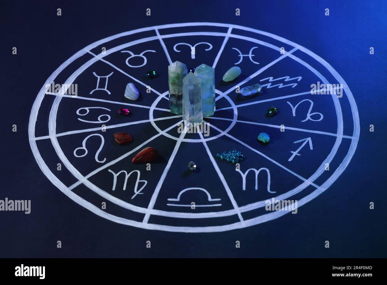 Pietre naturali per segni zodiacali e grafico astrologico disegnato su sfondo blu scuro Foto Stock