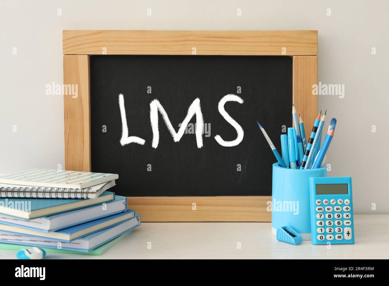 Sistema di gestione dell'apprendimento. Lavagna piccola con abbreviazione LMS su tavolo leggero con cancelleria Foto Stock