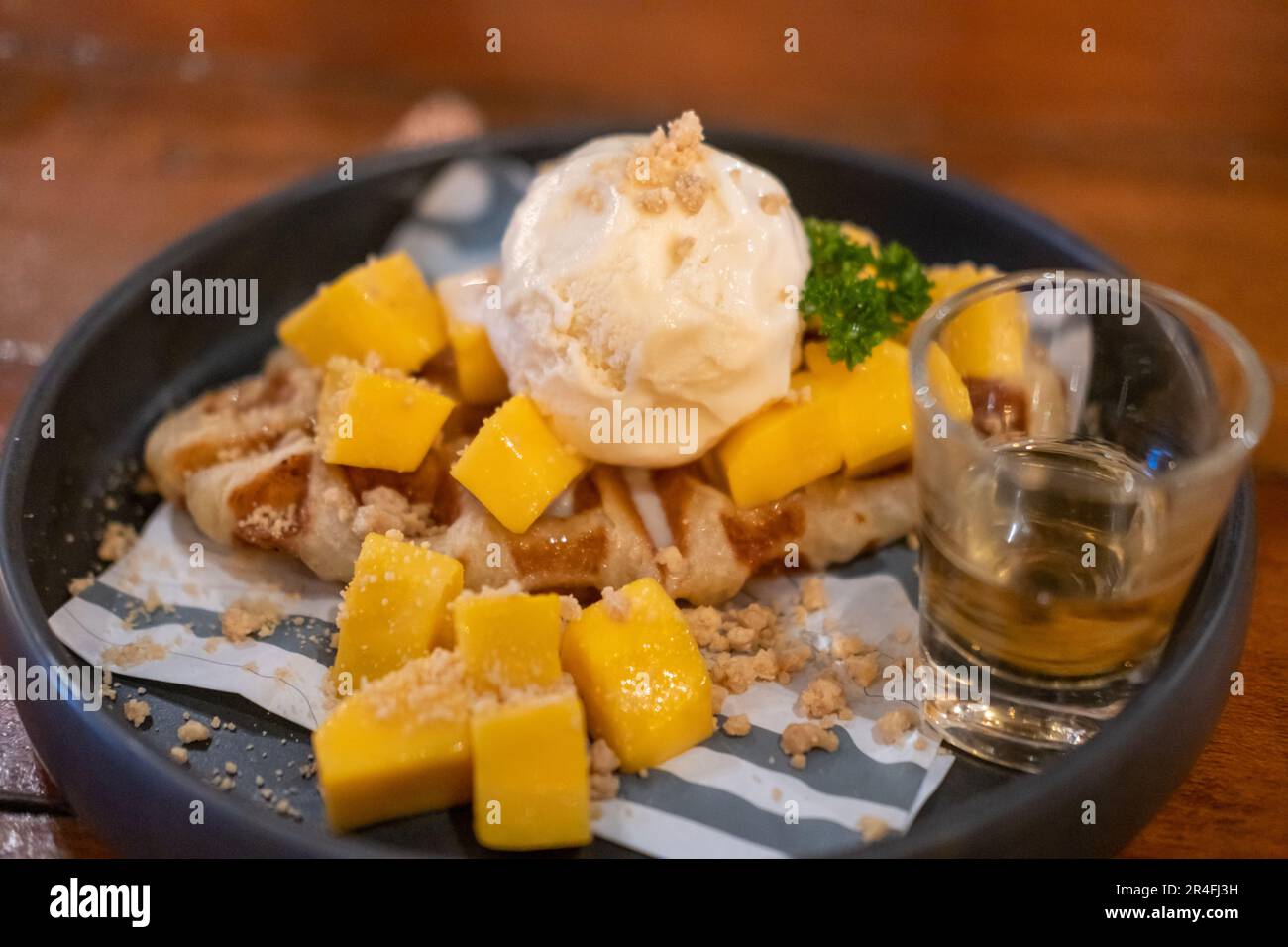 Crostini, ibrido di croissant e waffle al mango, gelato e miele serviti sul piatto Foto Stock