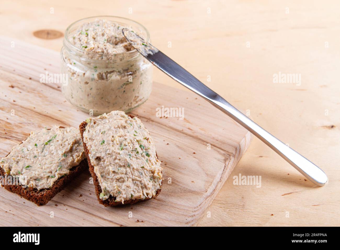 Assapora la ricchezza di pane bruno a fette con deliziosa diffusione sullo sfondo rustico di legno Foto Stock