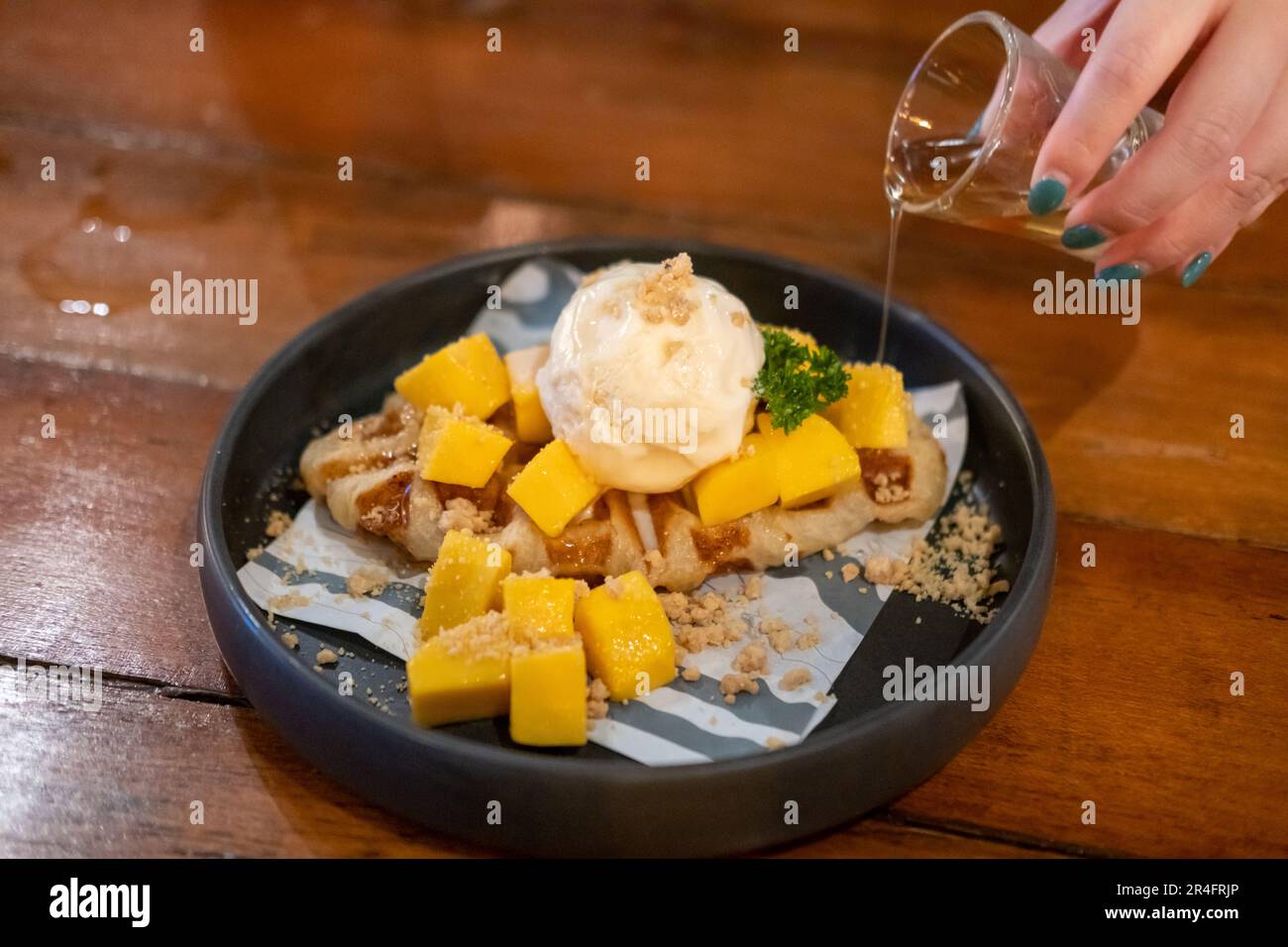 Crostini, ibrido di croissant e waffle al mango, gelato e miele serviti sul piatto Foto Stock