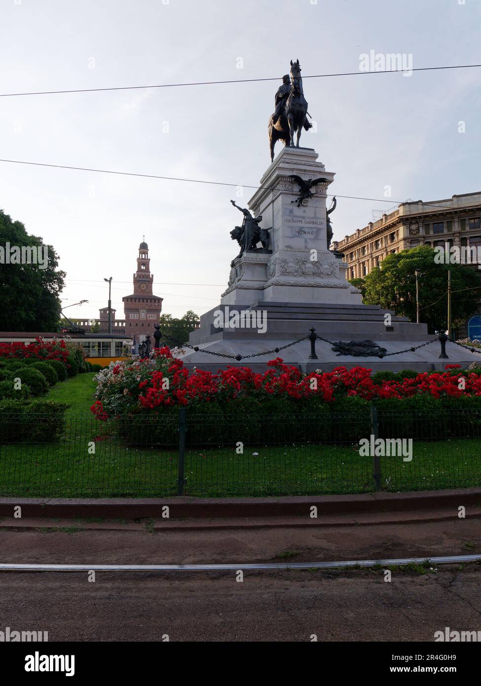 Statua equestre di Garibaldi circondata da fiori a largo Cairoli, Castello Sforzesco alle spalle, Milano, Lombardia, Italia Foto Stock