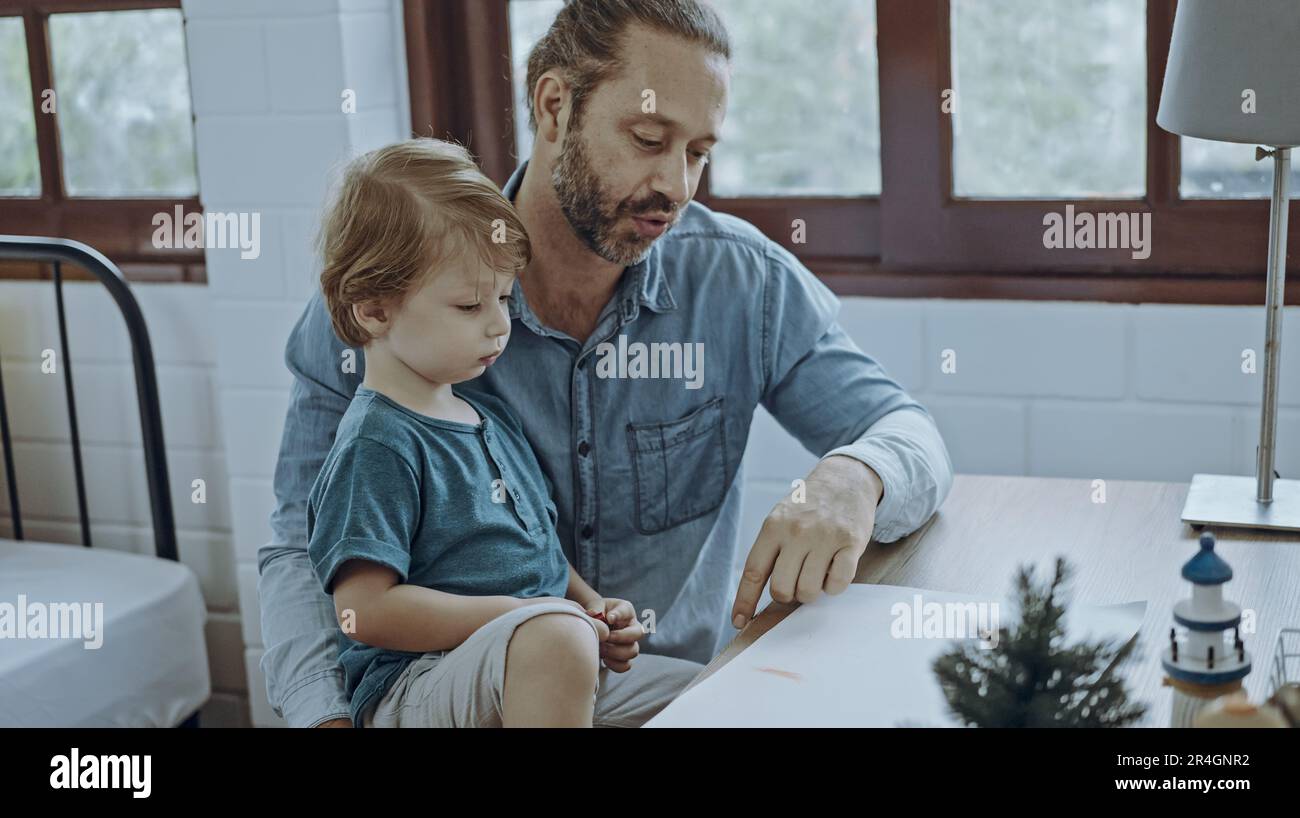 Famiglia caucasica pittura su carta con figlio in casa. Little Son imparare a disegnare l'immagine d'arte Godetevi la creatività con il padre in casa. Foto Stock
