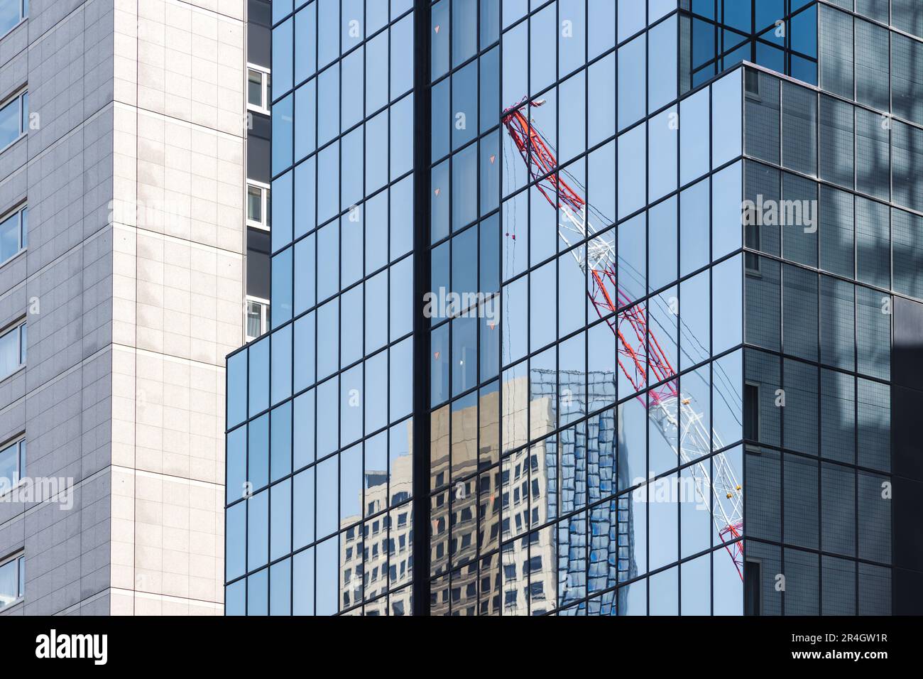 immagine di una gru da costruzione che si riflette nelle finestre di edifici alti e moderni Foto Stock