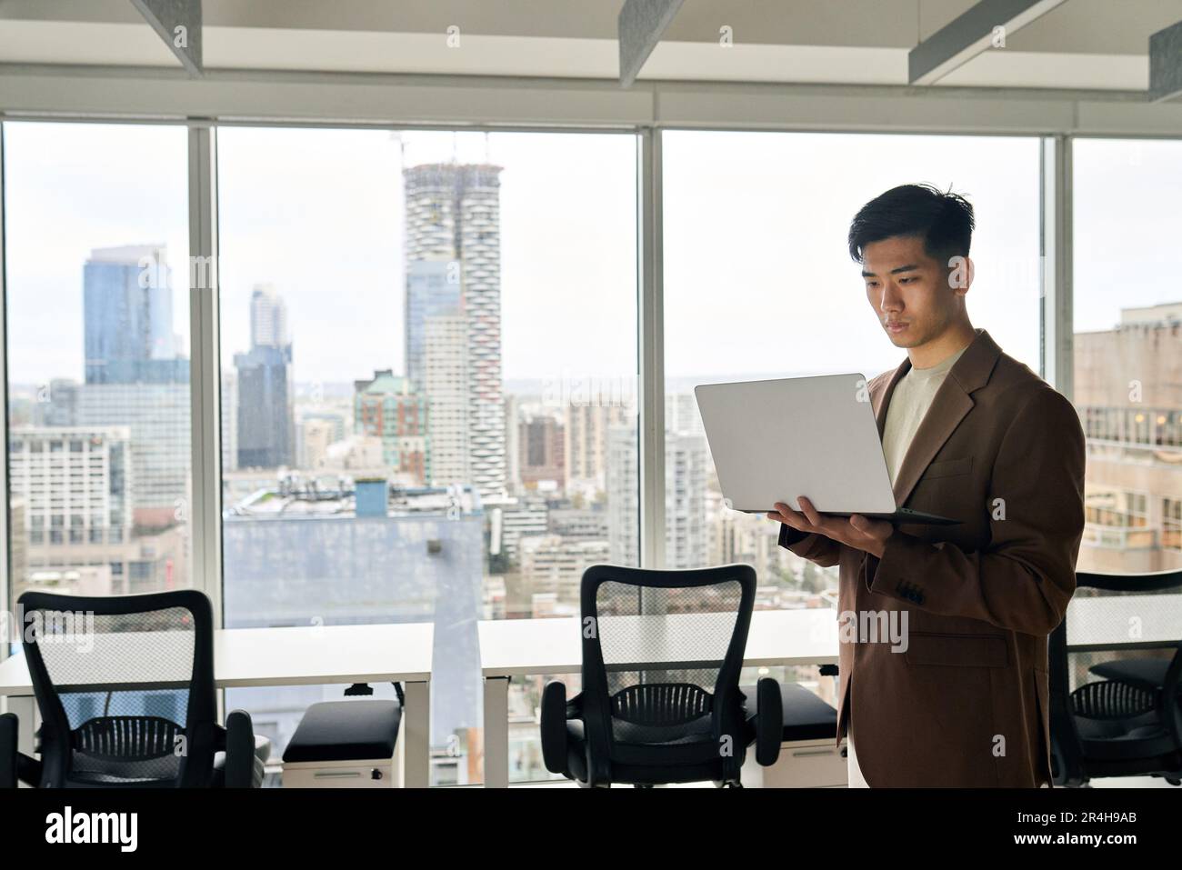 Giovane uomo d'affari asiatico serio che lavora su un notebook in ufficio. Foto Stock