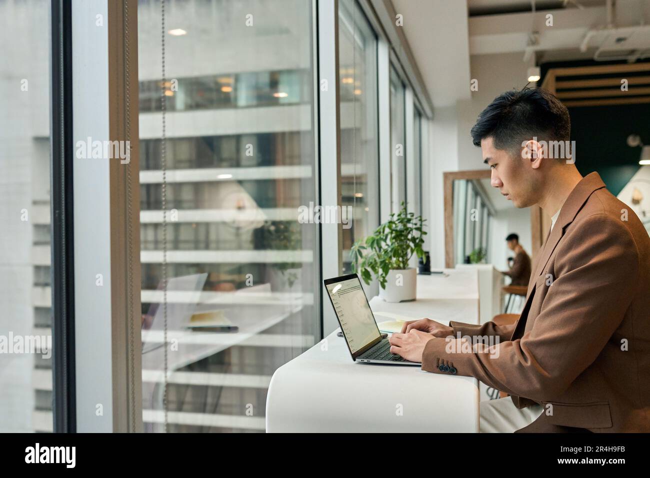 Giovane uomo d'affari asiatico impegnato che lavora su un computer portatile in ufficio. Foto Stock