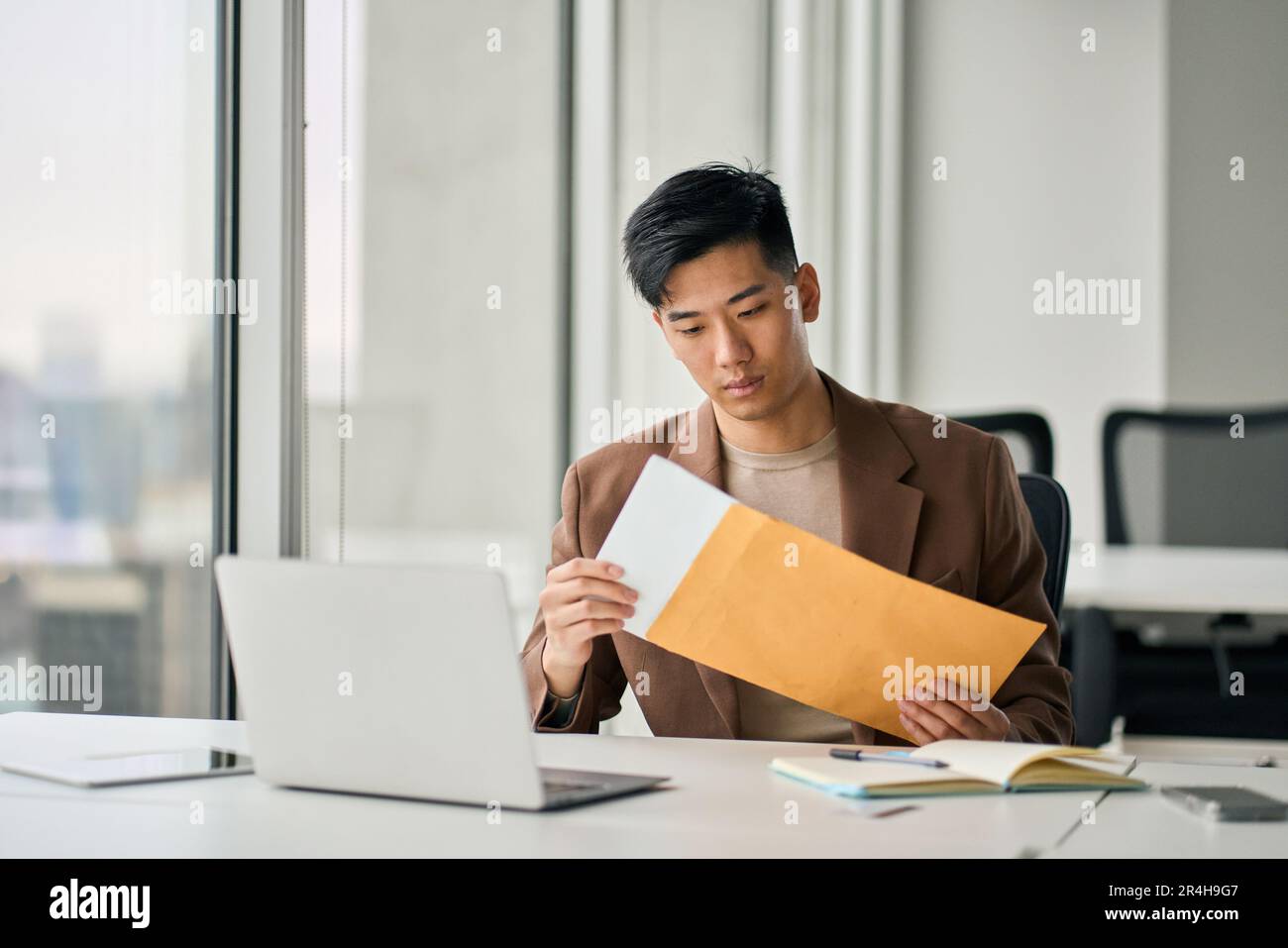 Giovane uomo d'affari asiatico professionale che riceve la lettera di posta di affari in ufficio. Foto Stock