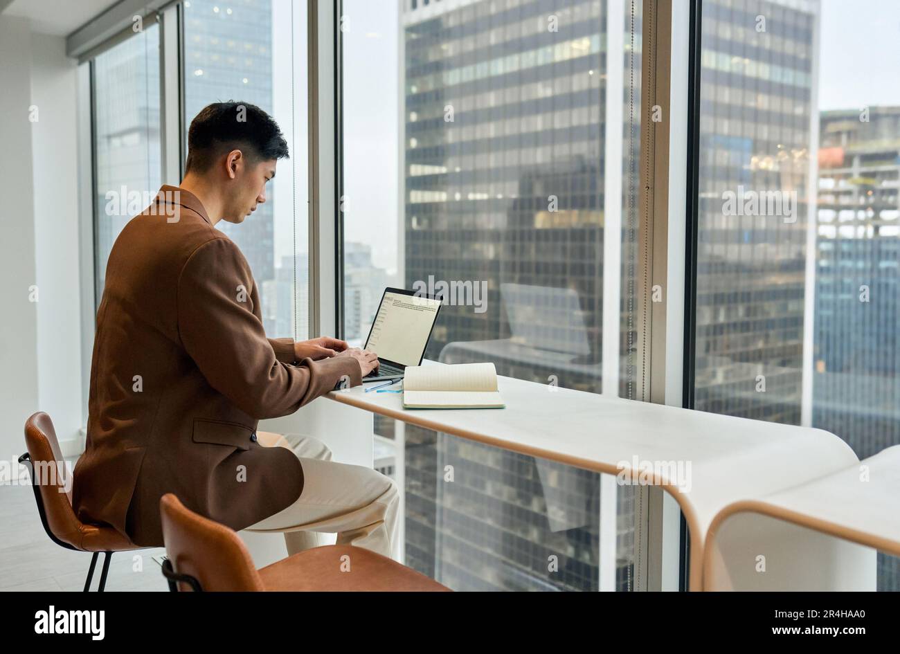 Giovane uomo d'affari asiatico impegnato a lavorare su un computer portatile in ufficio. Foto Stock
