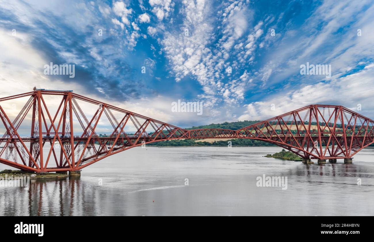 Vista di due carrozze locali ScotRail treno a sbalzo Forth Rail Bridge con acqua calma, Firth of Forth, Scozia, Regno Unito Foto Stock