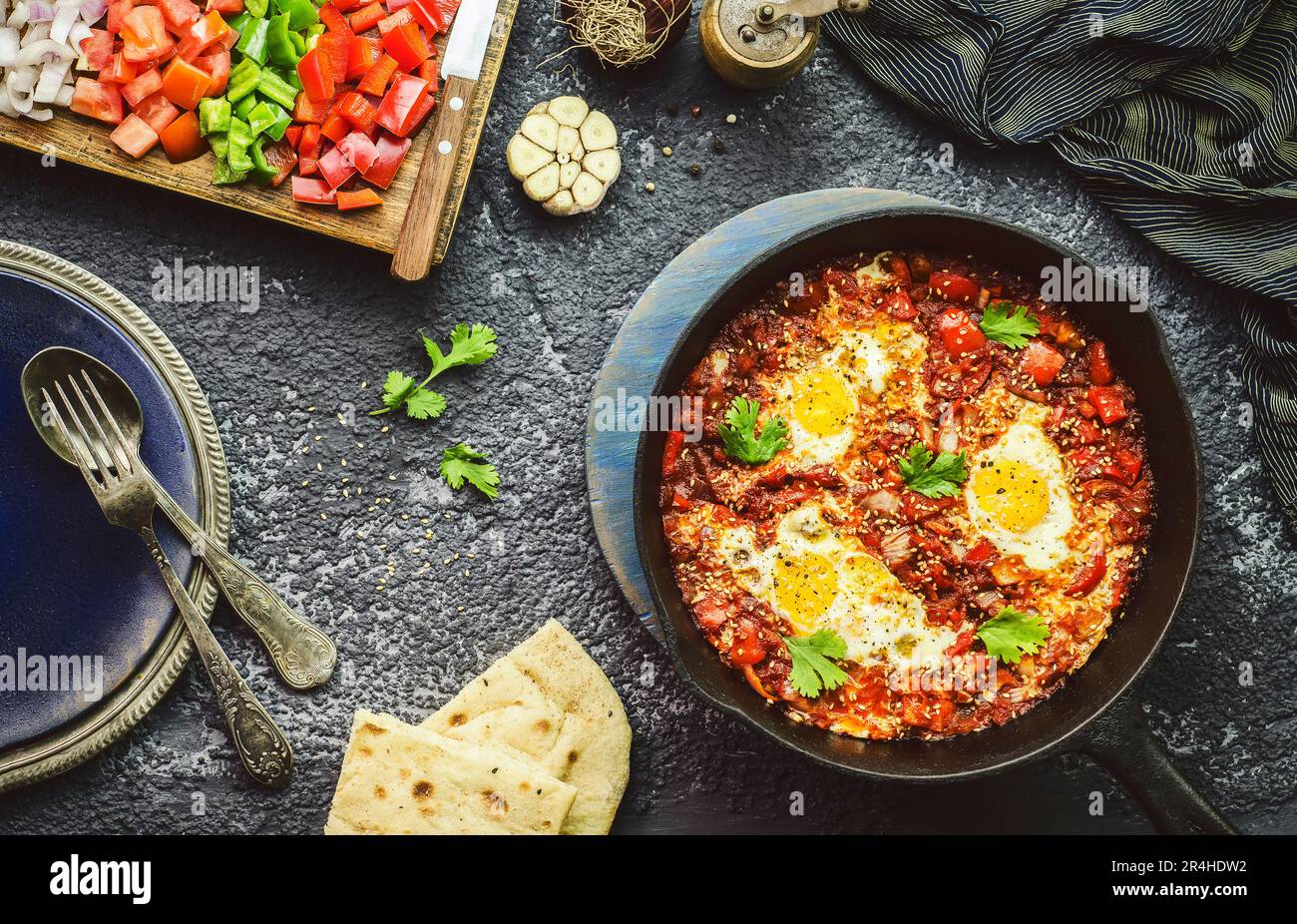 Cibo tradizionale mediorientale; padella Shakshuka servita con pane pita e con verdure fresche tritate. Vista dall'alto con primo piano Foto Stock