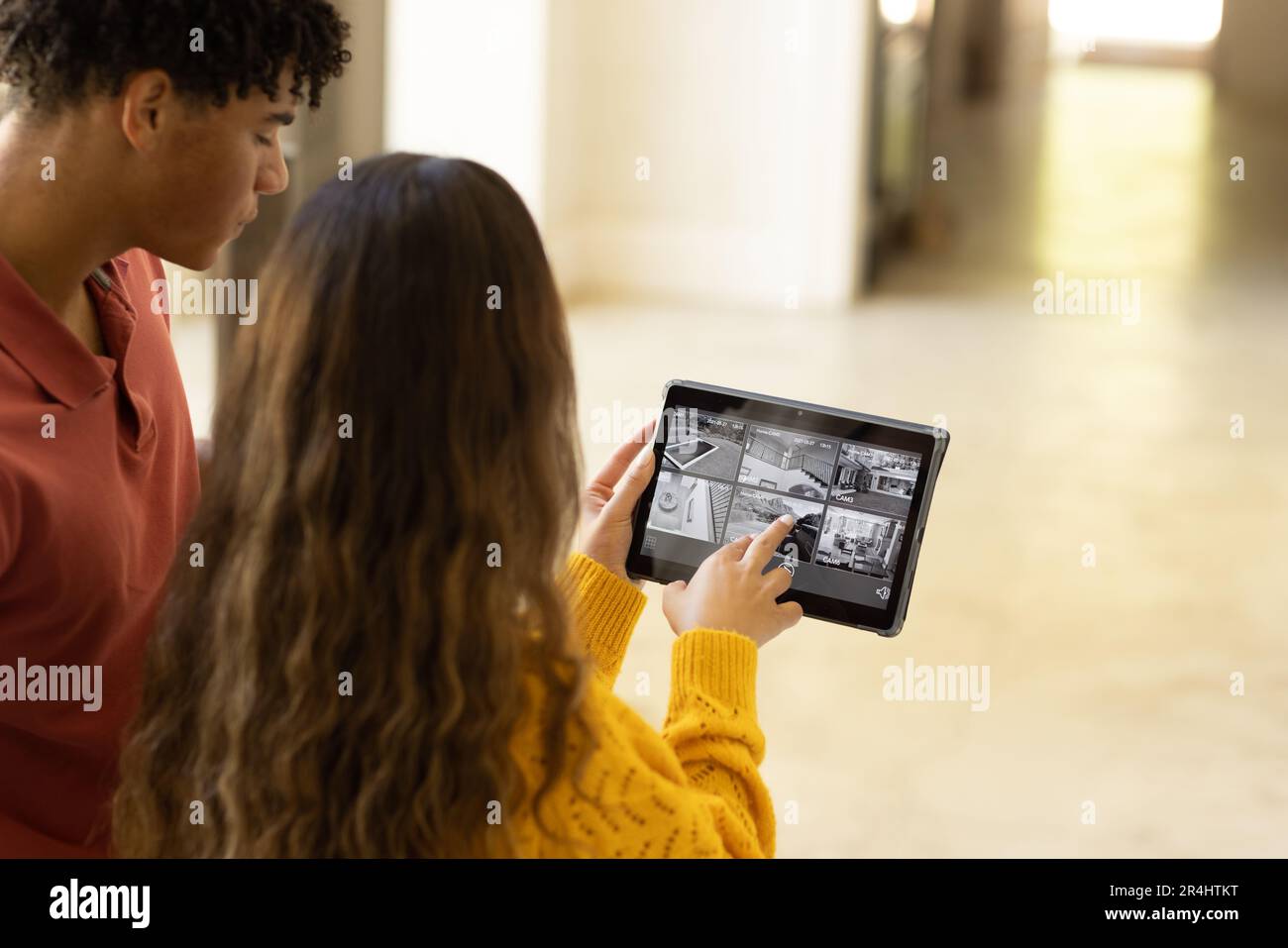 Giovane coppia biraciale che controlla la casa intelligente con videocamera su tablet digitale Foto Stock