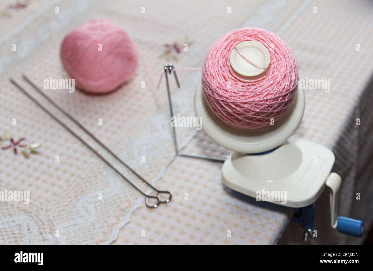 Processo di avvolgimento del filato di lana rosa dal groviglio all'avvolgimento, utilizzando un avvolgitore sul tavolo Foto Stock