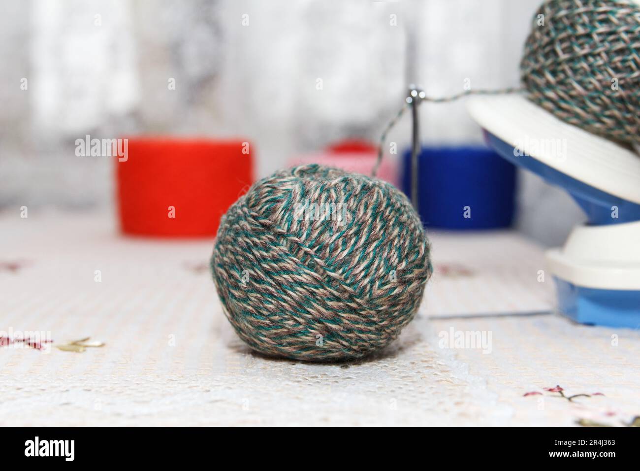 Il processo di avvolgimento del filo verde di lana dal groviglio all'avvolgimento, utilizzando un avvolgitore sul tavolo Foto Stock