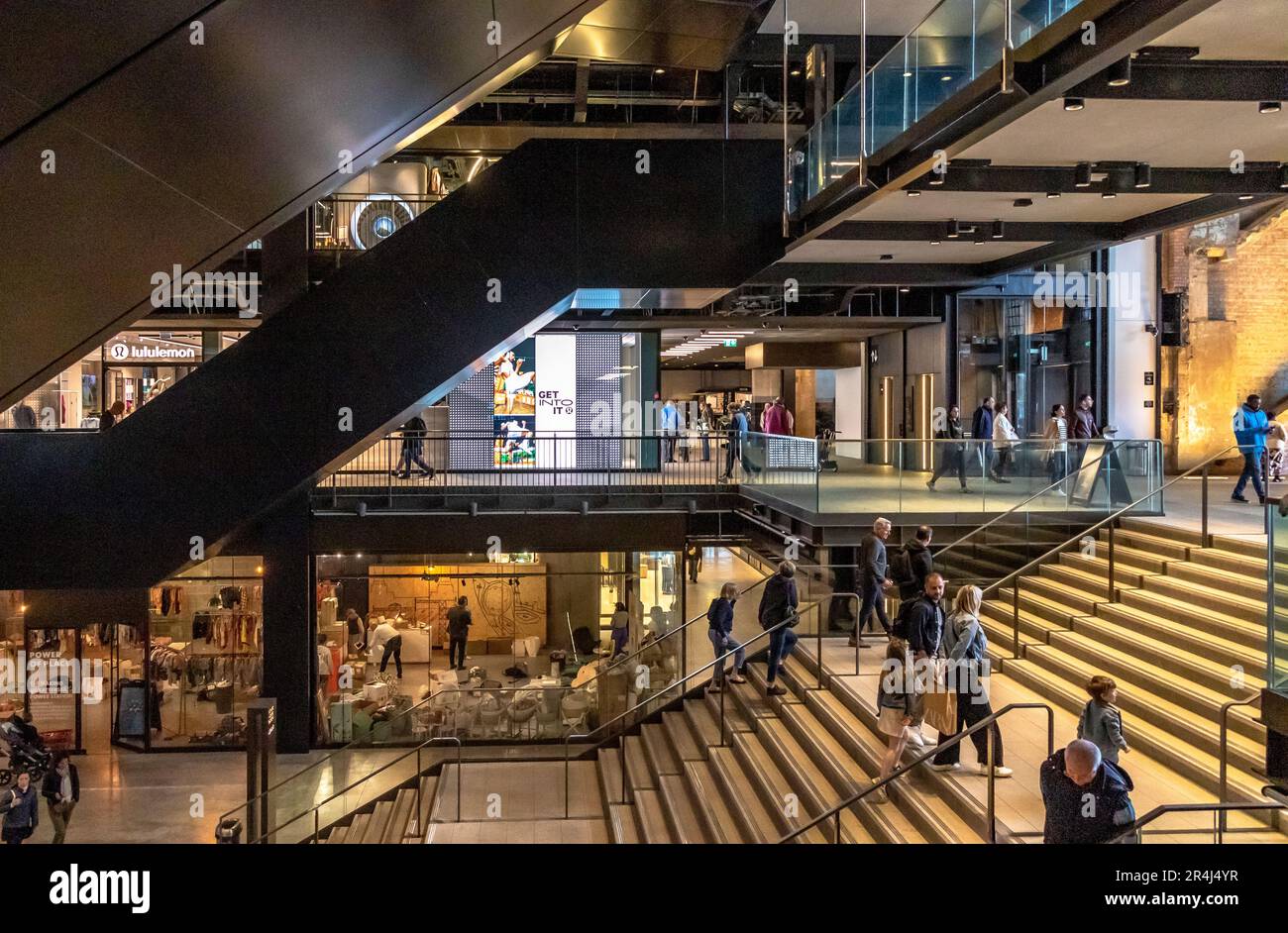 Persone sulle scale e scale mobili presso l'atrio dell'ingresso sud della centrale elettrica di Battersea, oggi una delle principali destinazioni per lo shopping e il tempo libero, Londra, SW11 Foto Stock