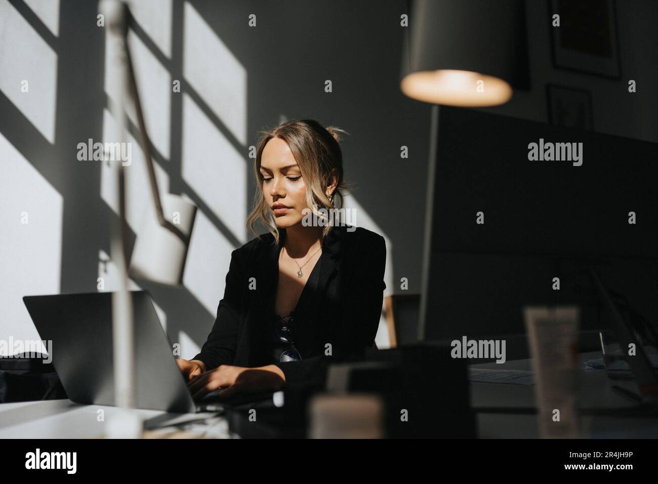 Giovane donna d'affari che lavora su un computer portatile seduto in ufficio Foto Stock