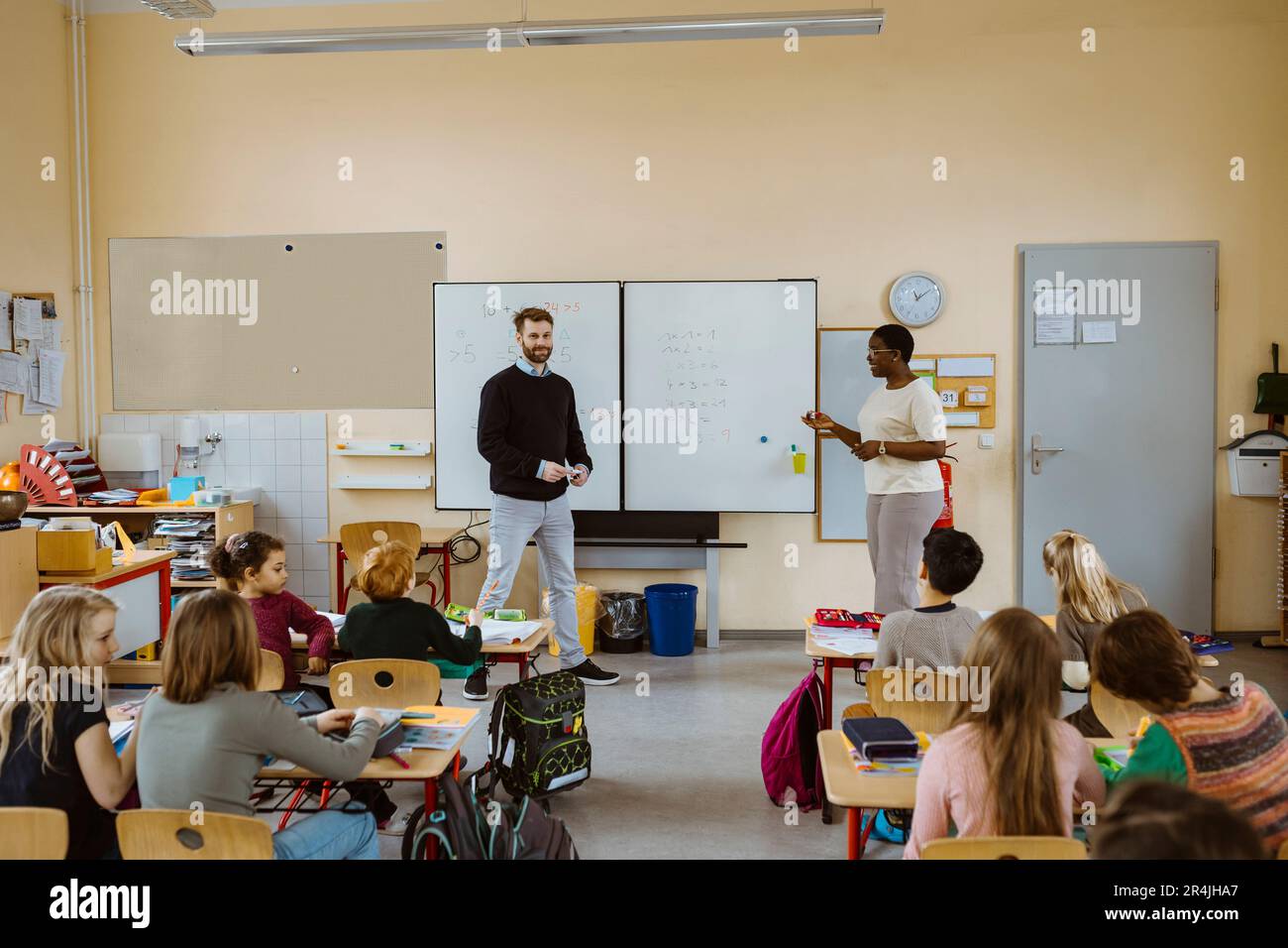 Insegnanti maschili e femminili che insegnano matematica agli alunni in classe Foto Stock