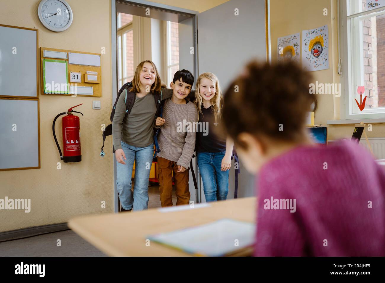 Amici felici con le braccia l'uno intorno all'altro che entrano in classe Foto Stock