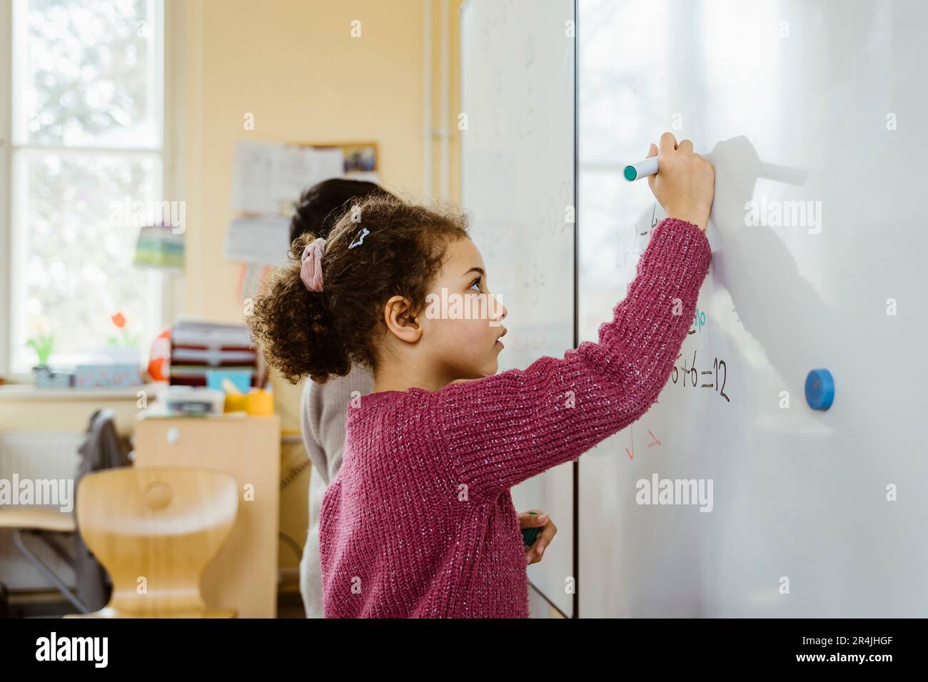 Vista laterale di una ragazza e di un ragazzo che scrivono sulla lavagna in aula Foto Stock