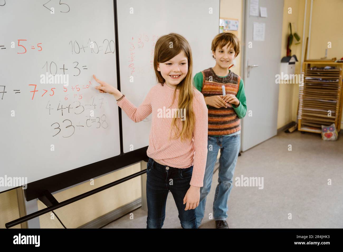 Ragazza felice risolvere il problema di matematica con il ragazzo in classe Foto Stock