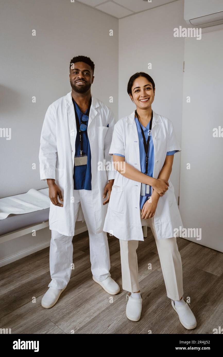 Sorridenti colleghi medici maschili e femminili in piedi in sala di consulenza Foto Stock