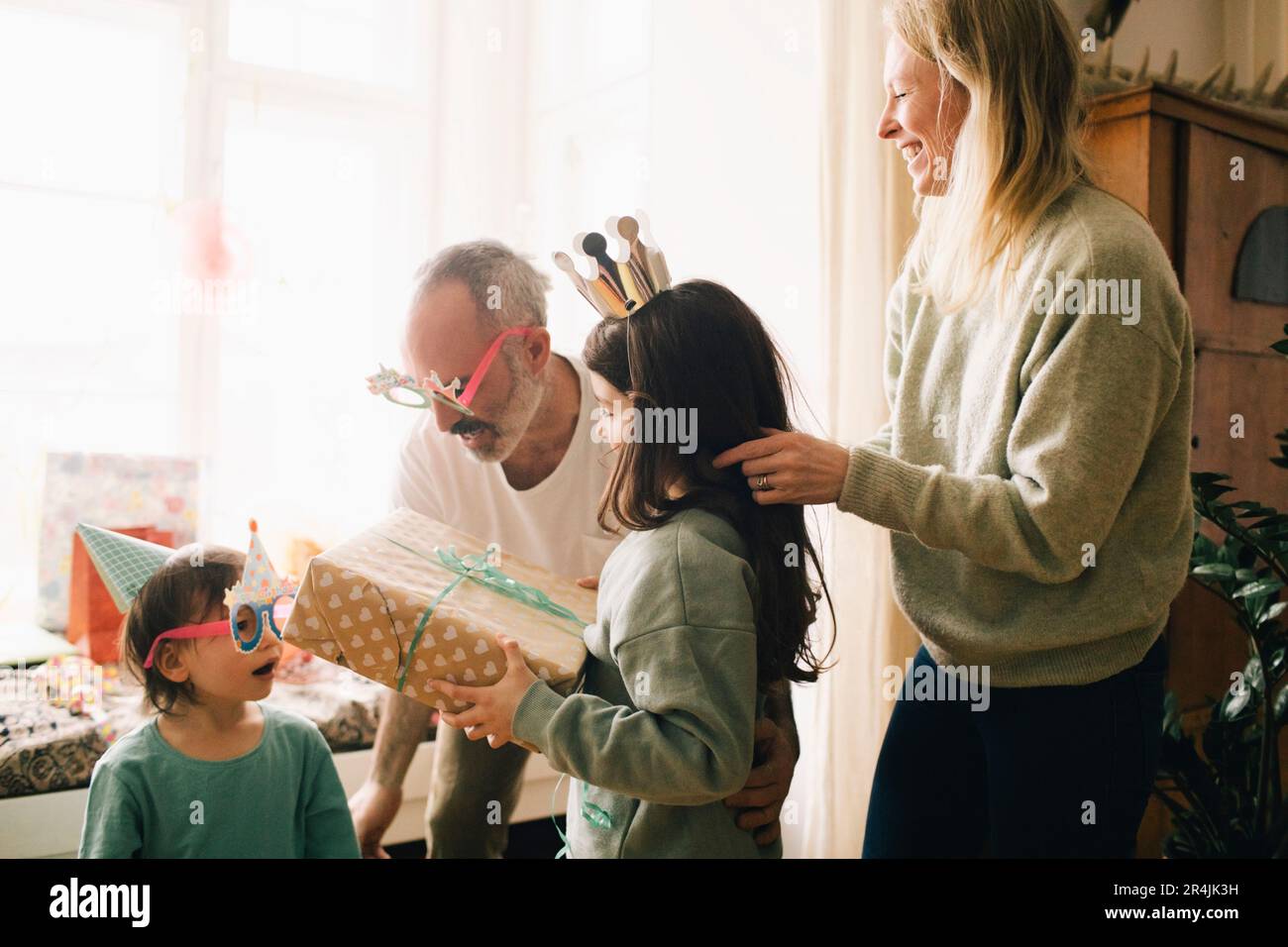 Genitori e bambini con un regalo di compleanno che si divertono a casa Foto Stock