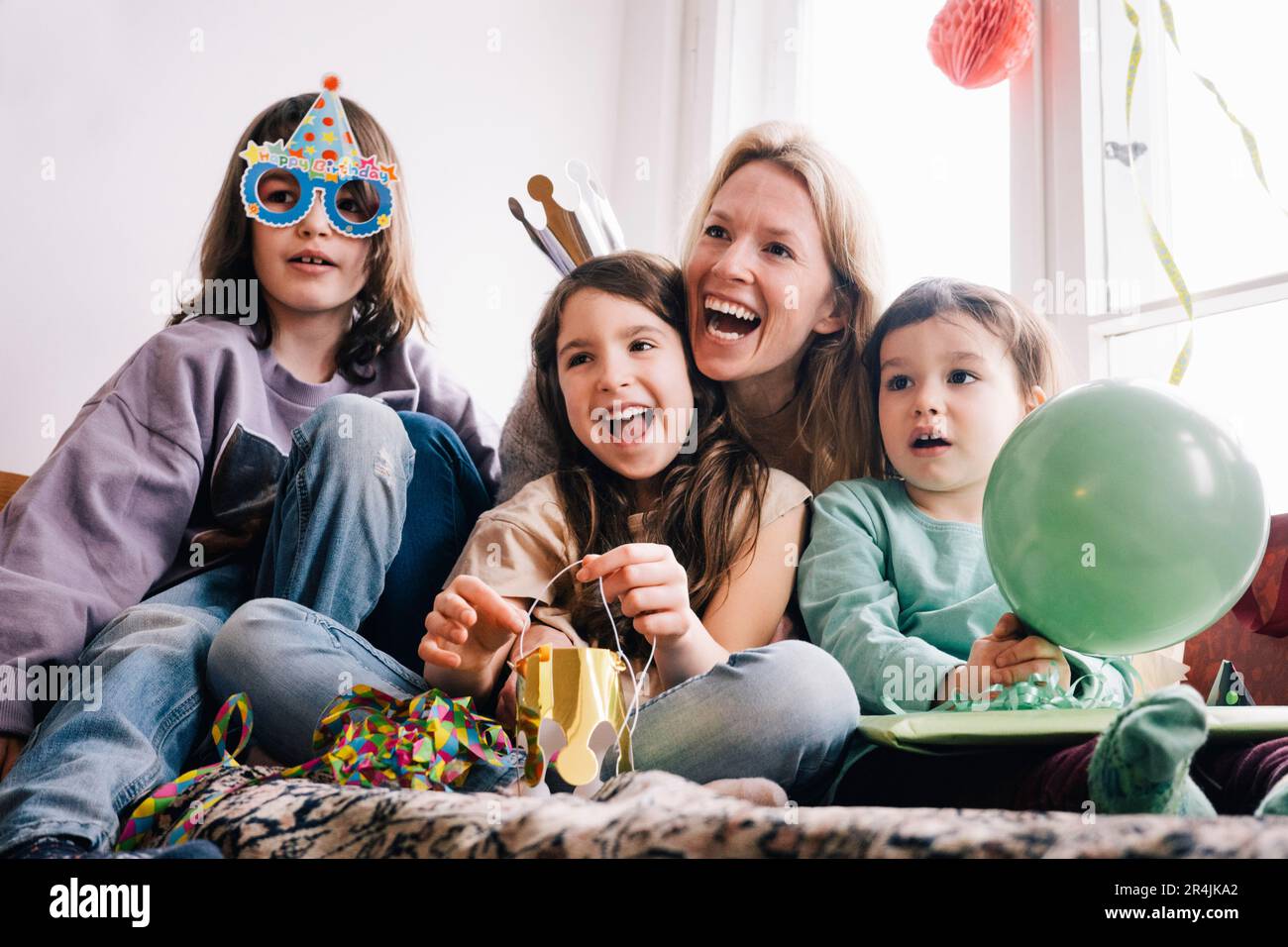 Madre allegra con i bambini che si divertano durante la festa di compleanno a casa Foto Stock