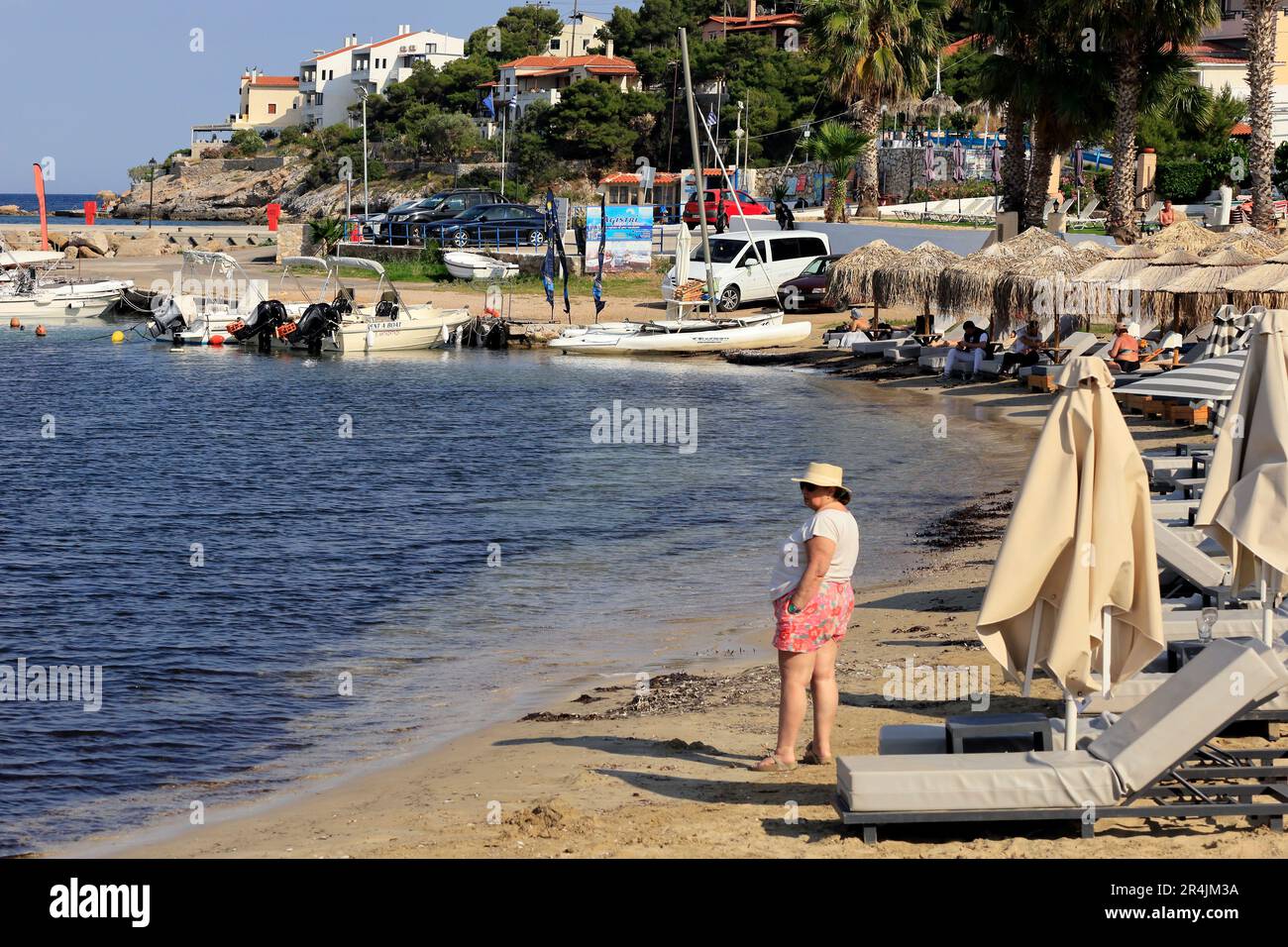 Donna anziana in un cappello da sole sulla spiaggia, Skala, Isola di Agistri, vicino ad Atene. Gruppo di isole Saroniche. Preso maggio 2023 Foto Stock Donna anziana in un cappello da sole sulla spiaggia, Skala, Isola di Agistri, vicino ad Atene. Gruppo di isole Saroniche. Preso maggio 2023 Foto Stock