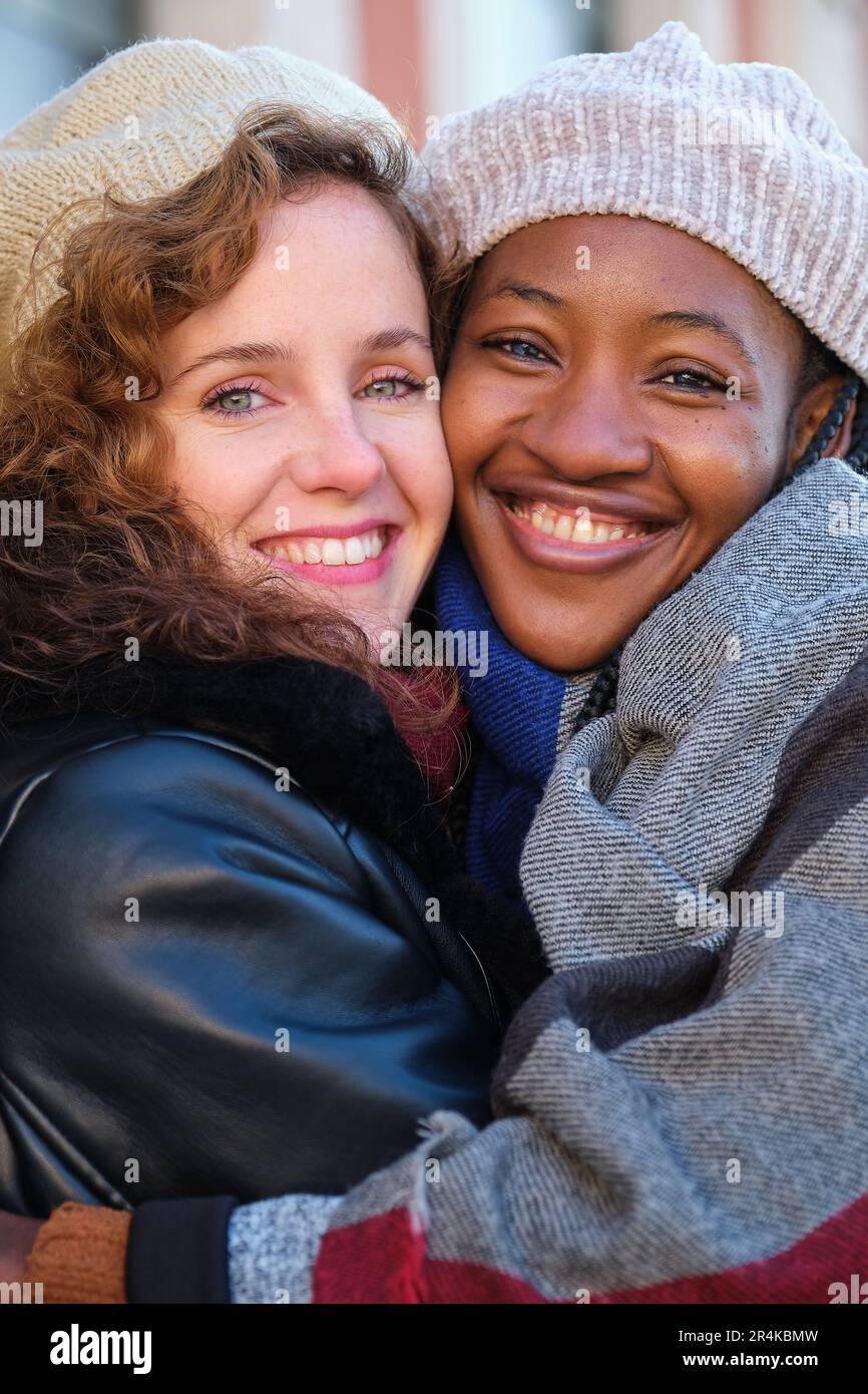Due donne multirazziali felici amici abbracciarsi e sorridere sulla strada della città. Foto Stock